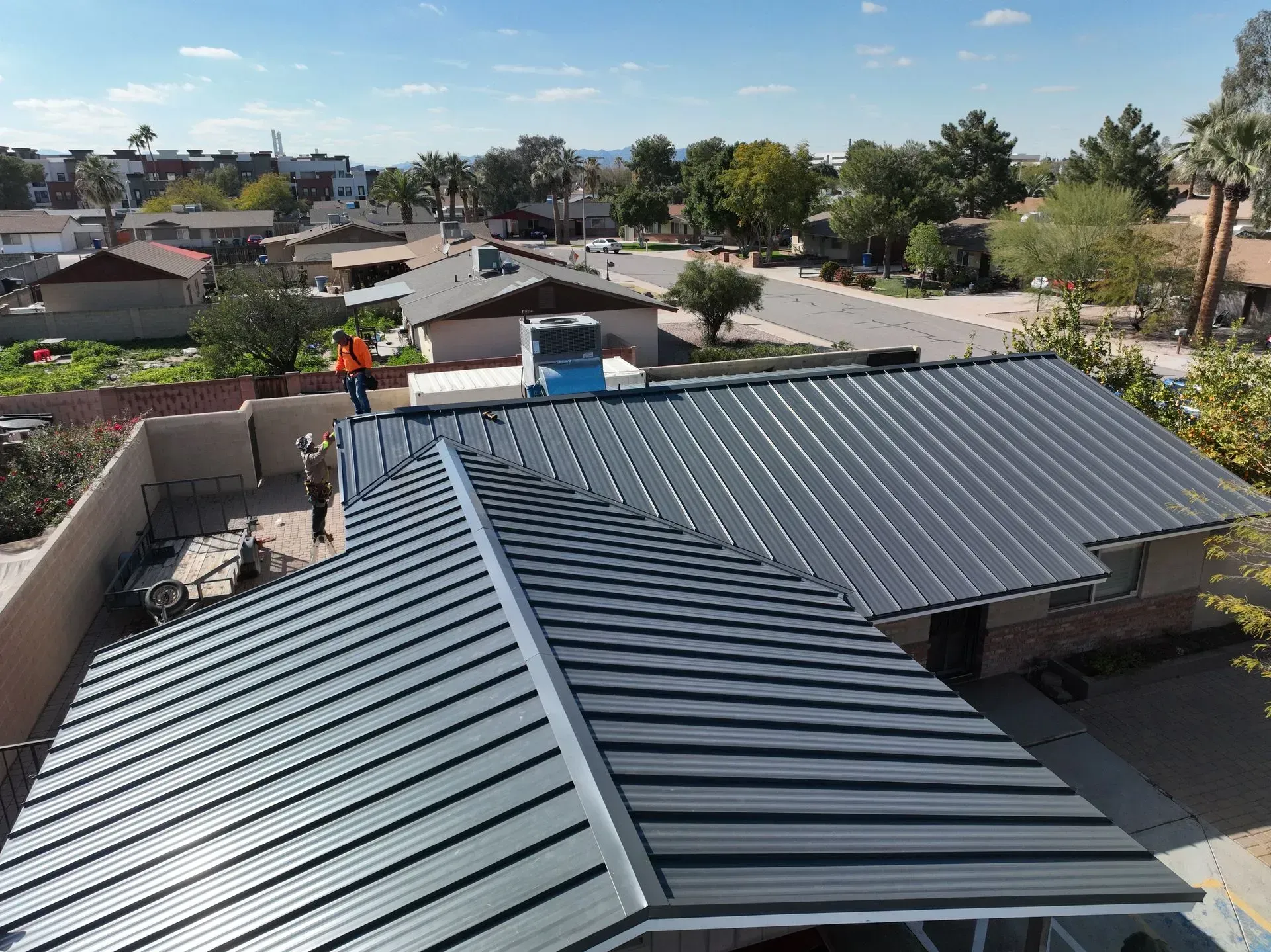 Rooftops with dark metal roofing overlooking a suburban neighborhood on a clear day
