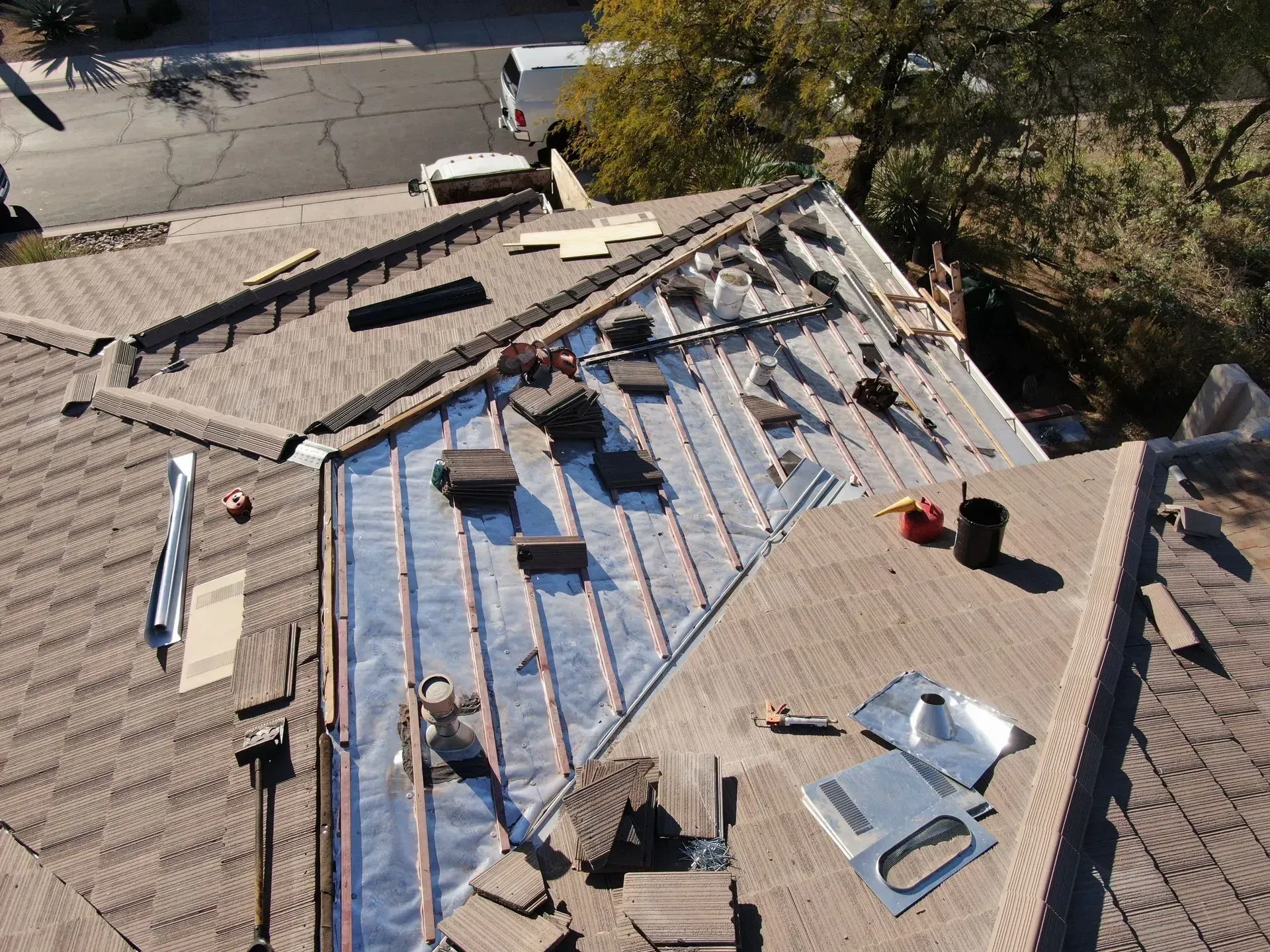 Roof under construction with shingles, underlayment, and two workers on a residential house