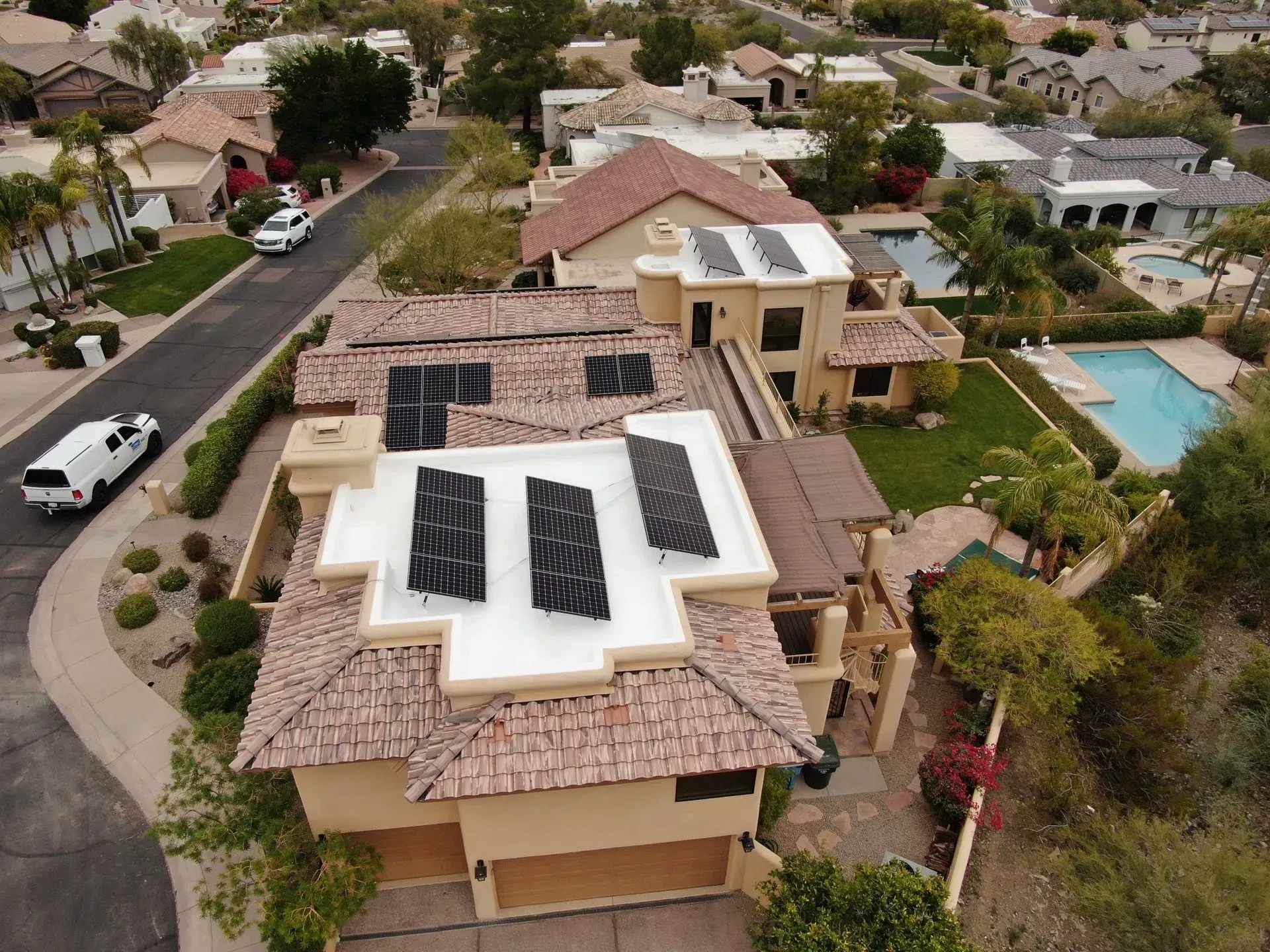 Aerial view of suburban homes with solar panels on rooftops and a swimming pool nearby