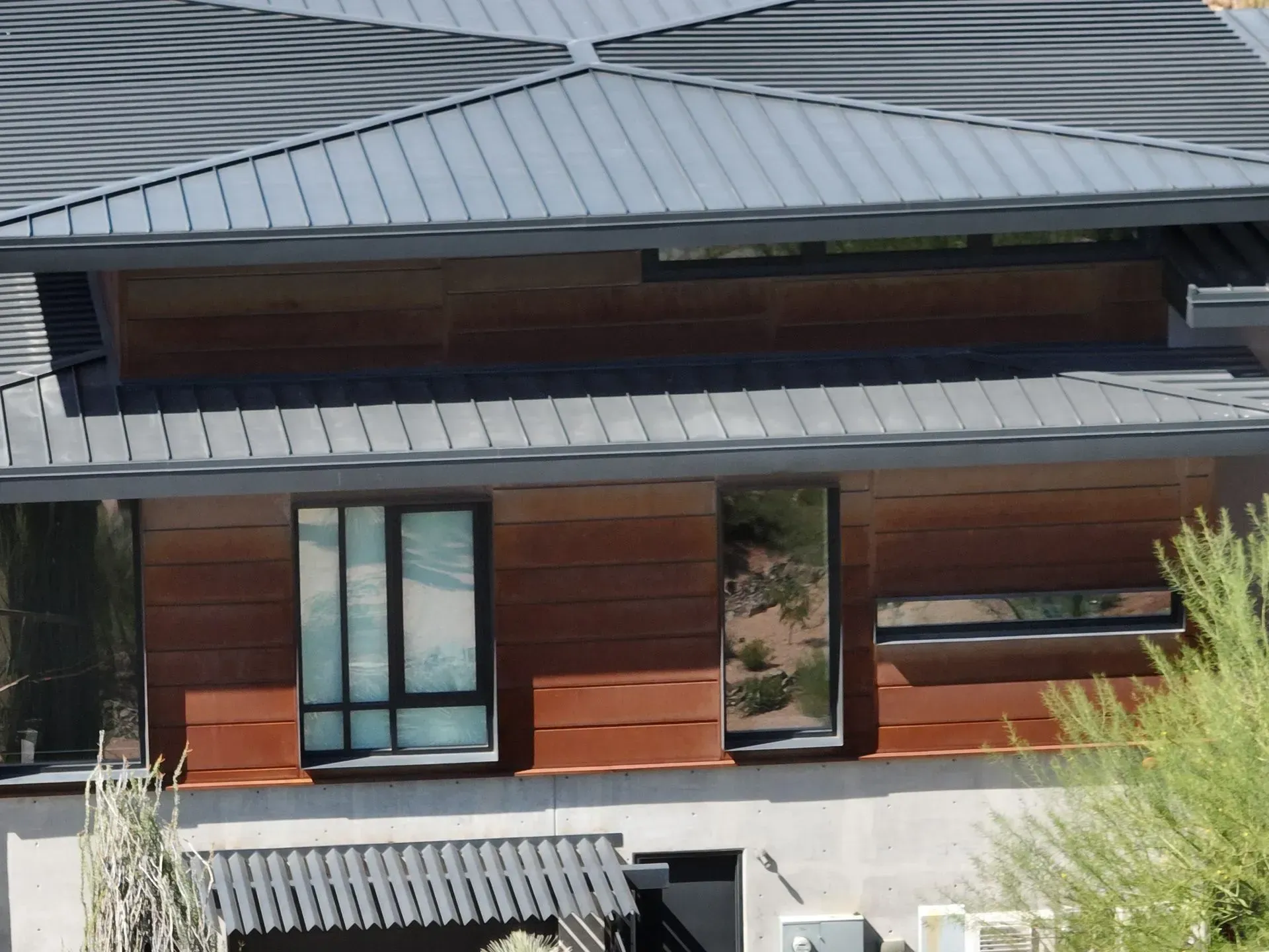 Modern house exterior with metal roof, wood siding, and large windows