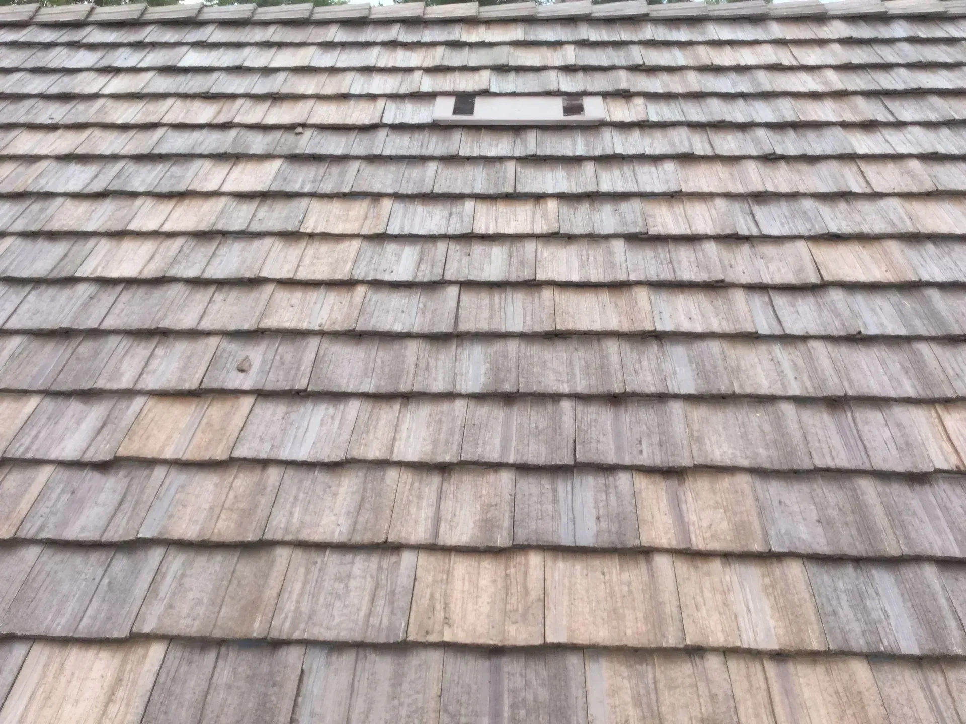 Weathered wooden shingle roof with a few dark vents near the ridge