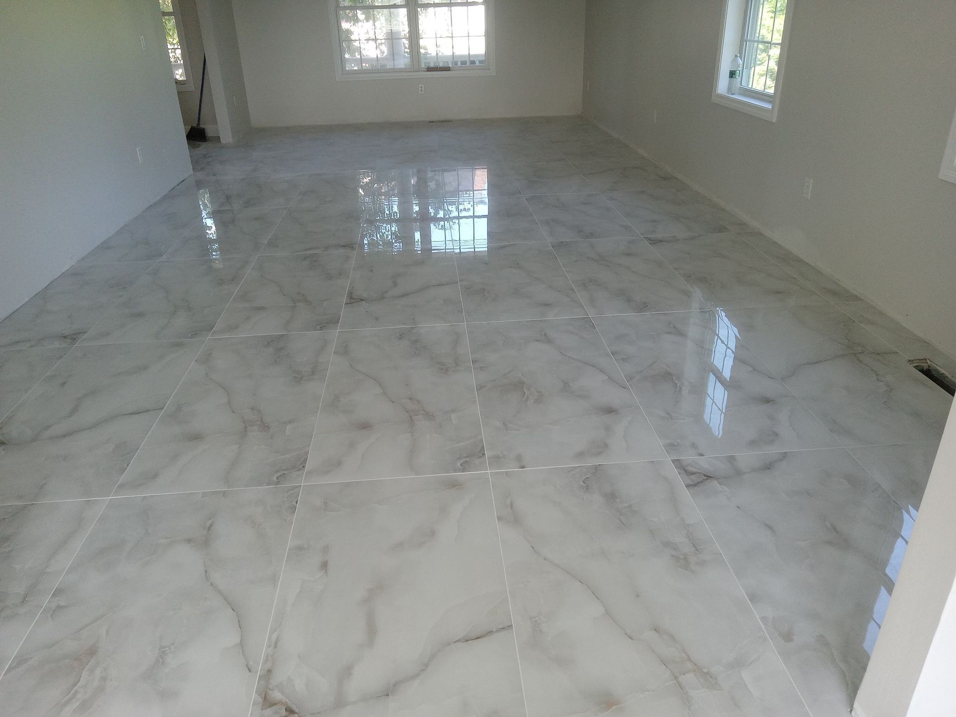 A large empty room with white tile floors and windows.