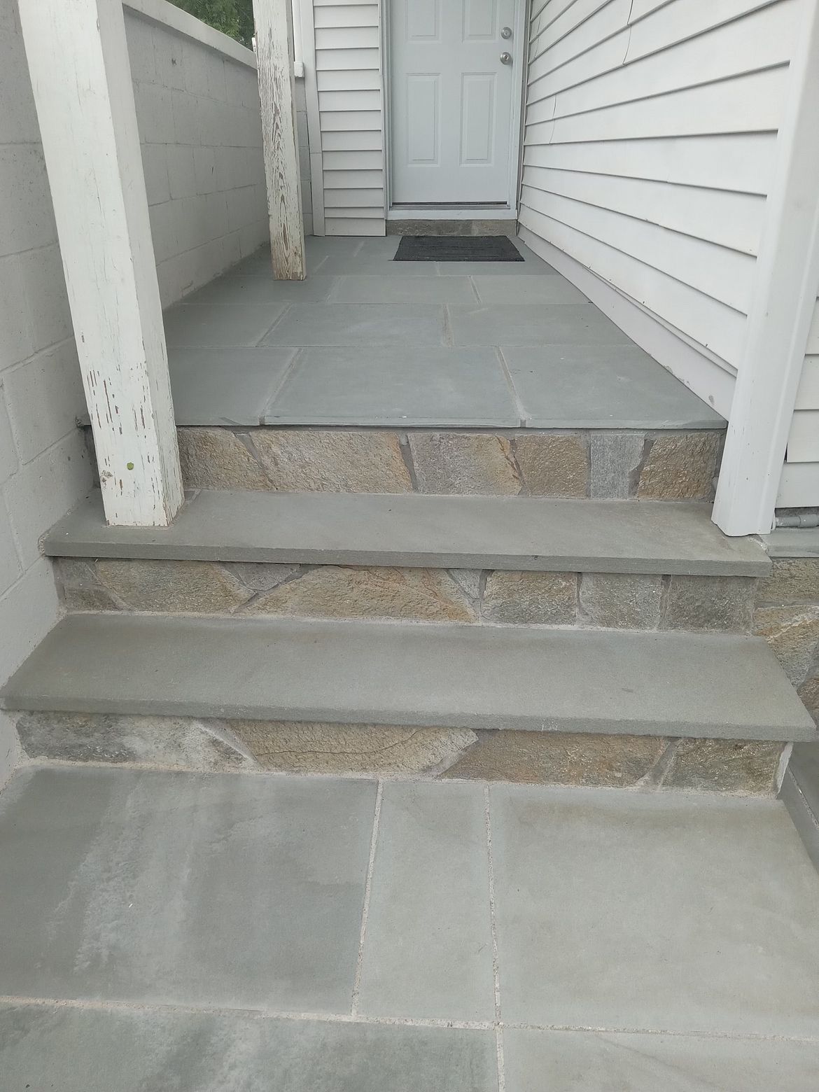 A stone porch with steps leading up to a white house.