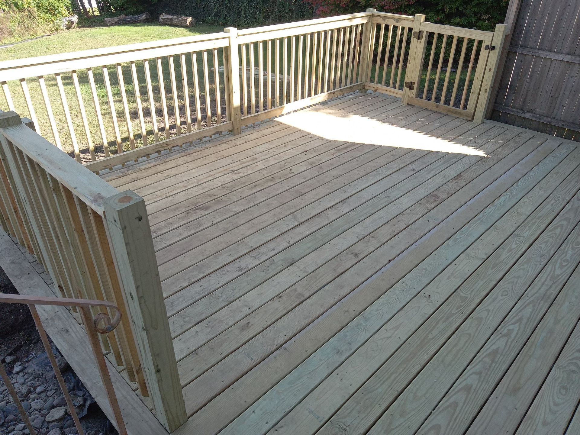 A wooden deck with a railing and a fence in the backyard.