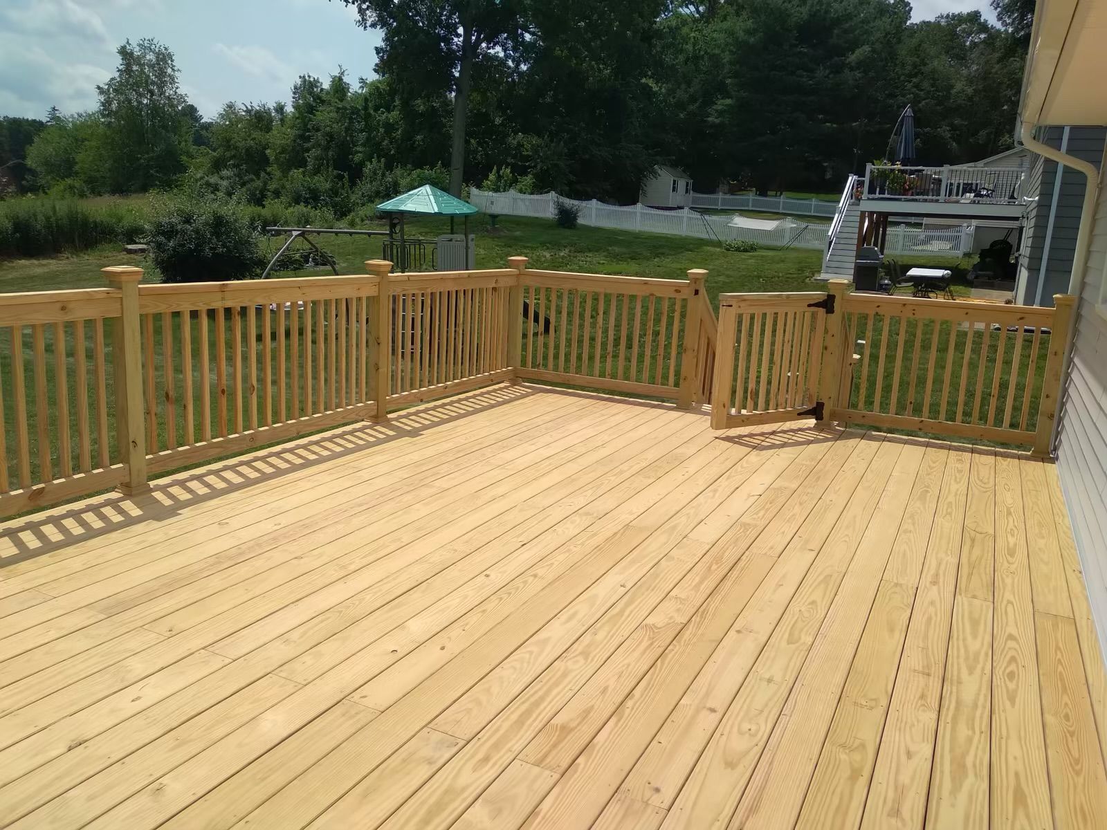 A large wooden deck with a wooden fence around it.