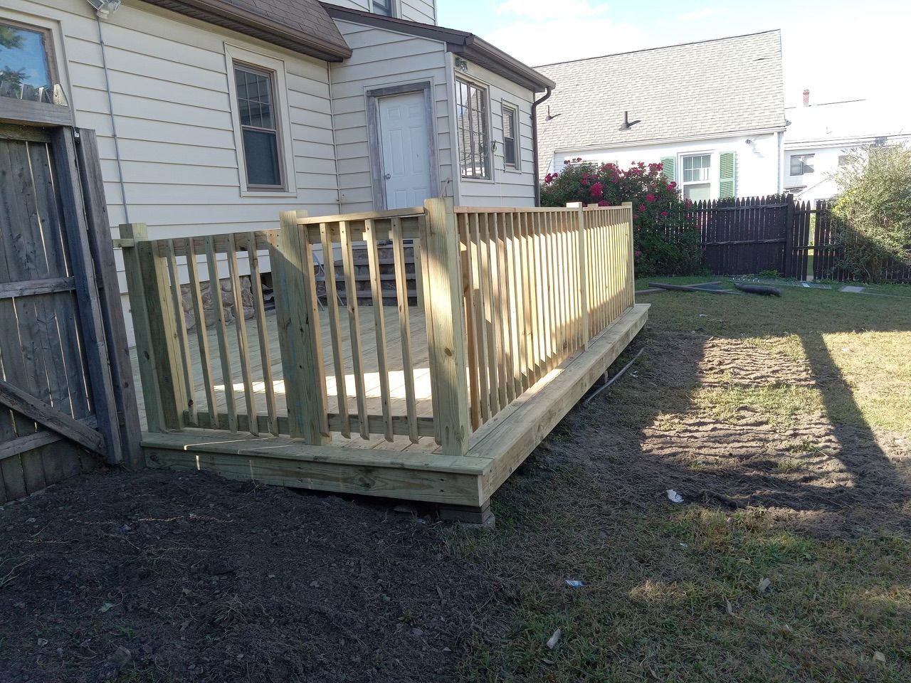 A wooden deck is in the backyard of a house.