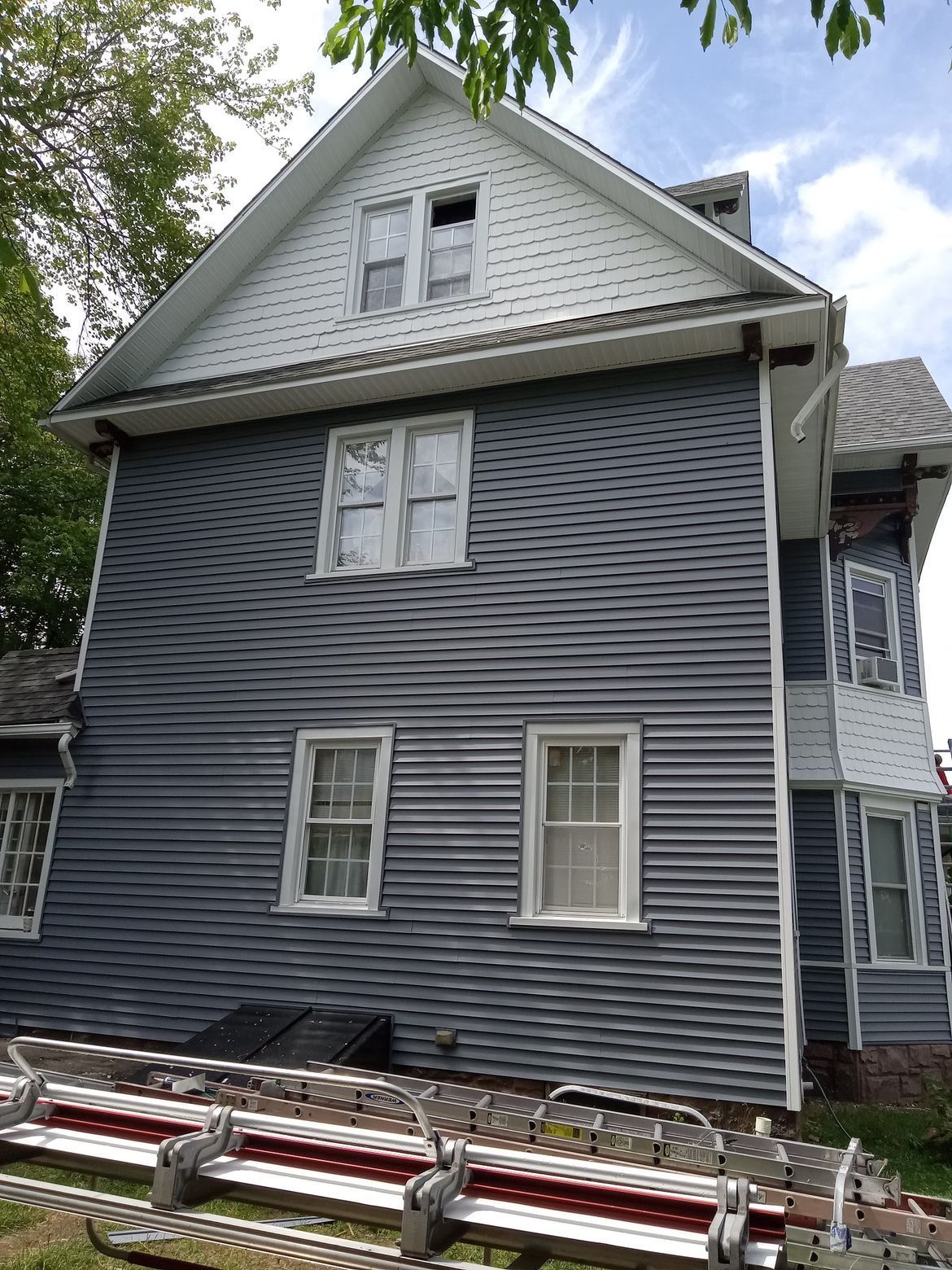 A gray and white house with a ladder in front of it