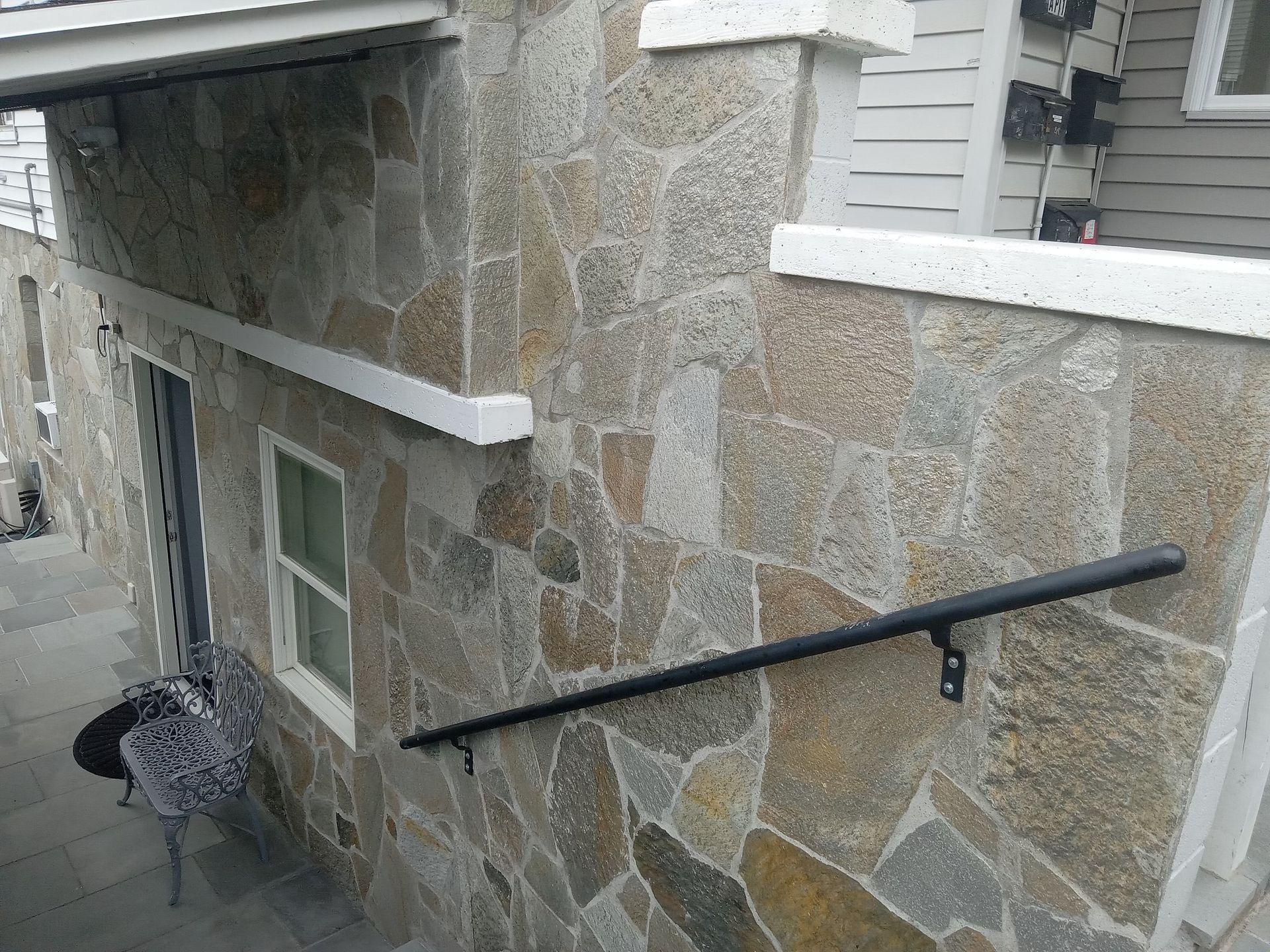 A stone wall with a black railing on it