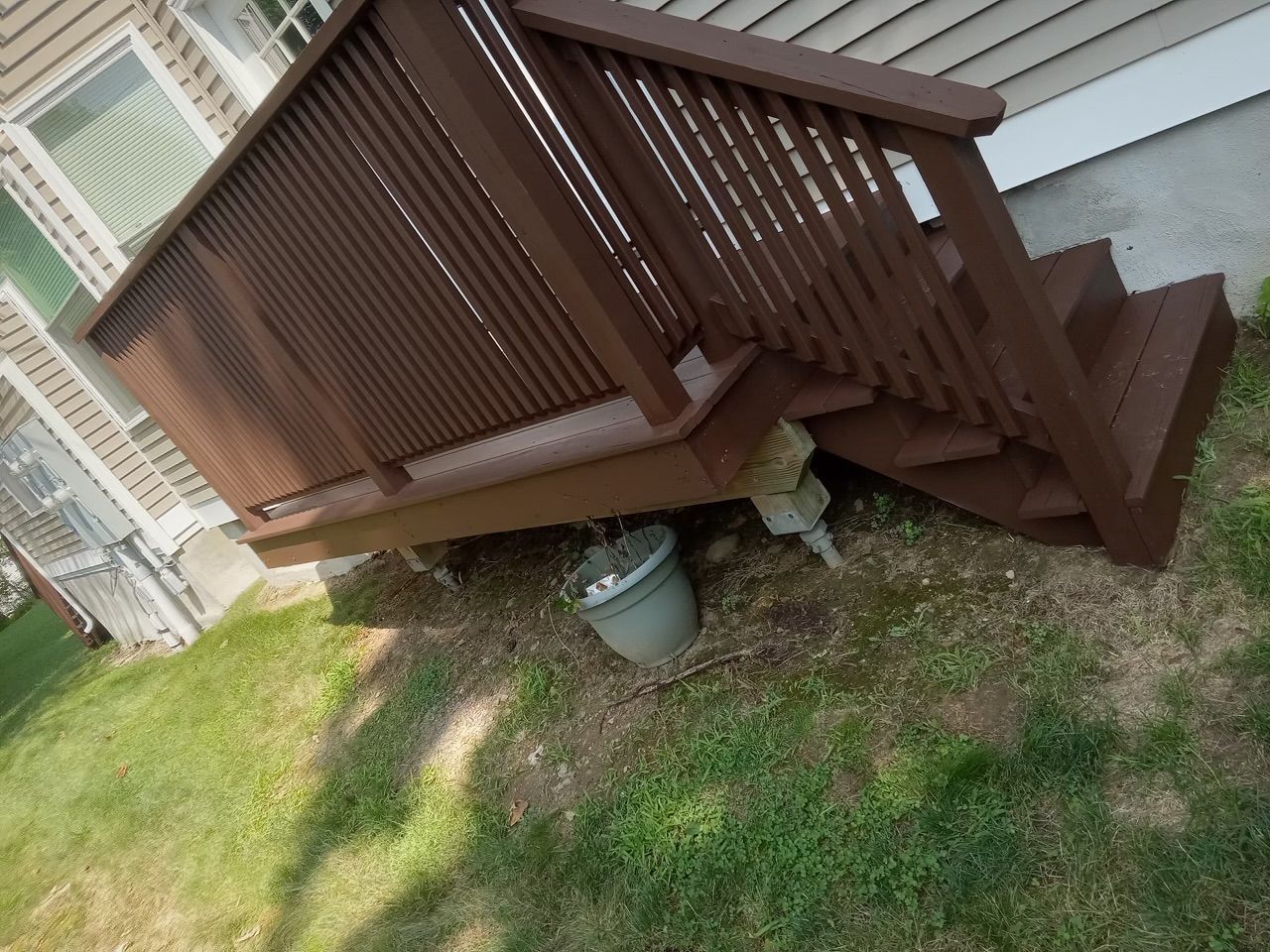 A wooden deck with stairs leading up to it next to a house.