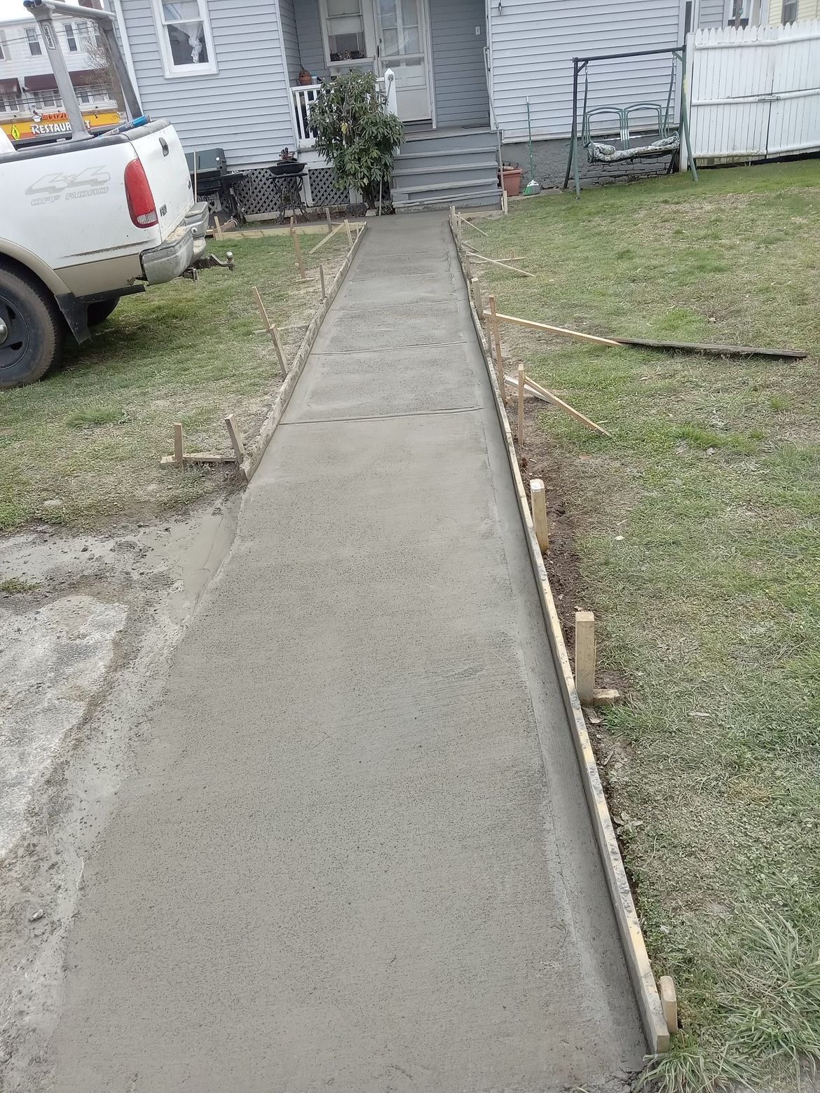 A concrete walkway is being built in front of a house.