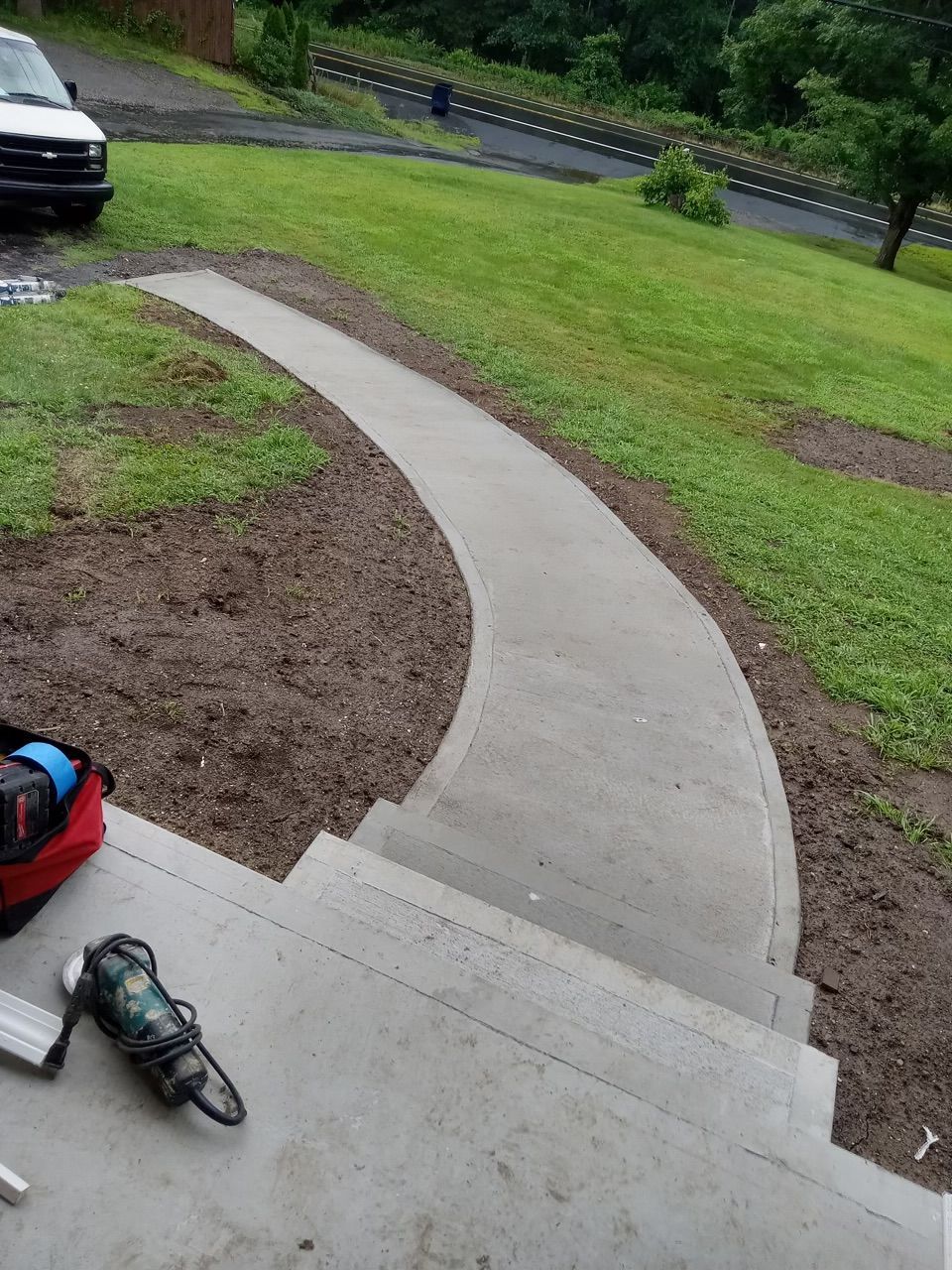 A concrete walkway is being built on the side of a house