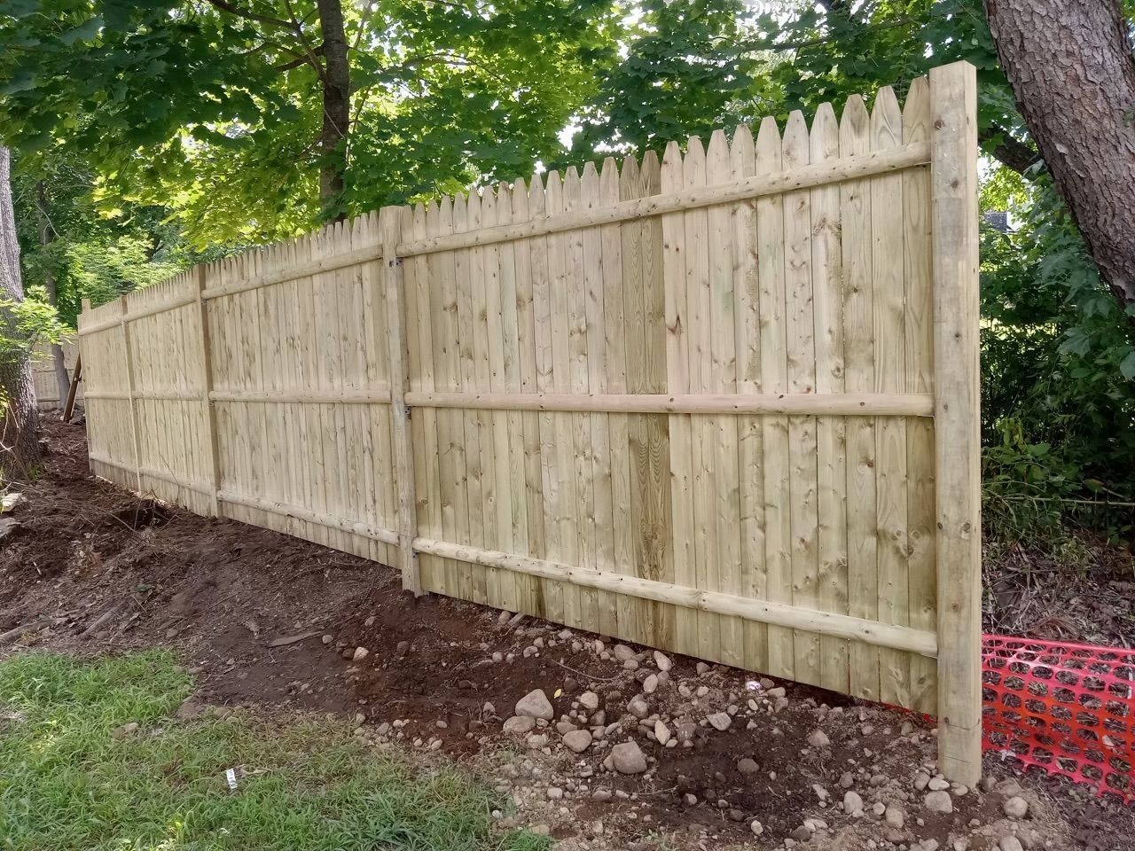 A wooden fence is sitting on top of a dirt hill.