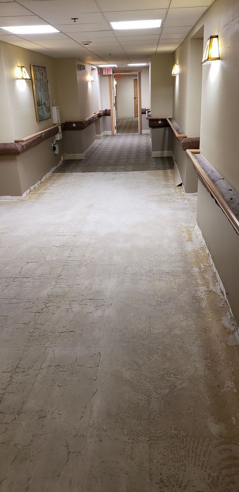 A long, brightly lit hallway with handrails on both sides, presumably in a care facility.