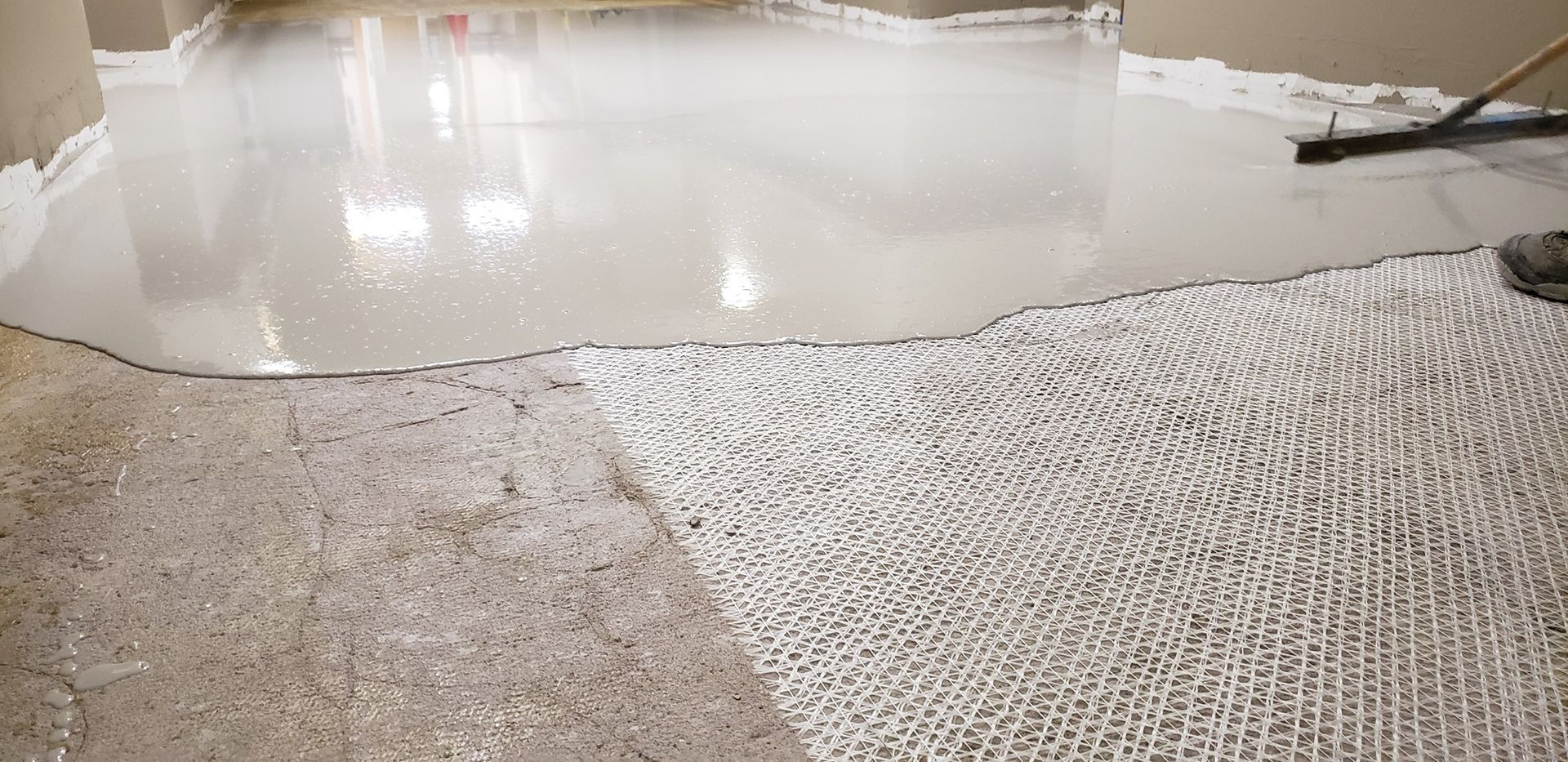 Floor being coated with a light-colored epoxy, showing a partially completed surface.