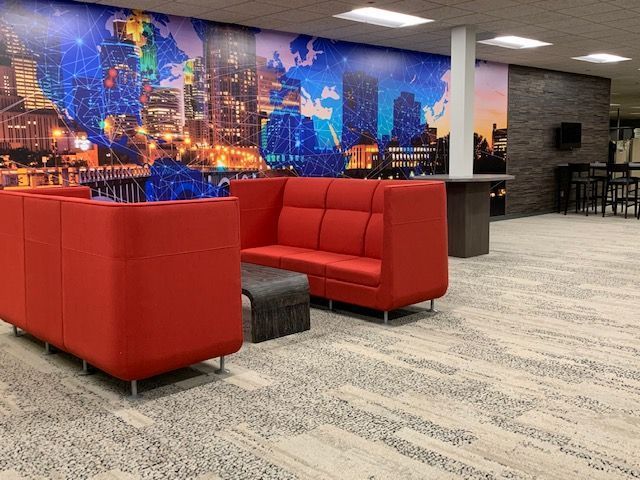 Red modern sofas in a lounge with world map mural, high-top table, and patterned carpet.