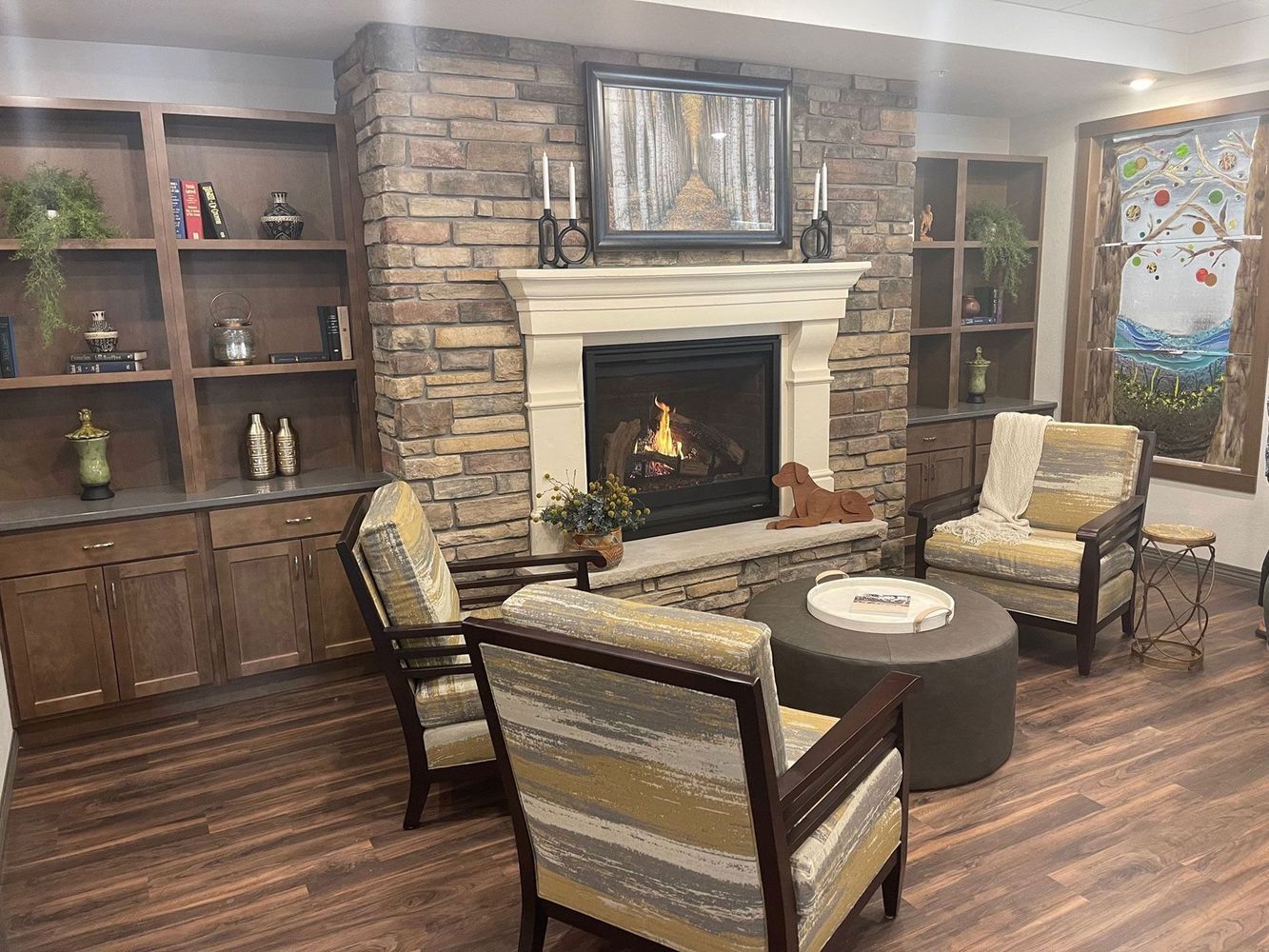 Cozy living room with fireplace, built-in shelves, and patterned armchairs on a wood floor.