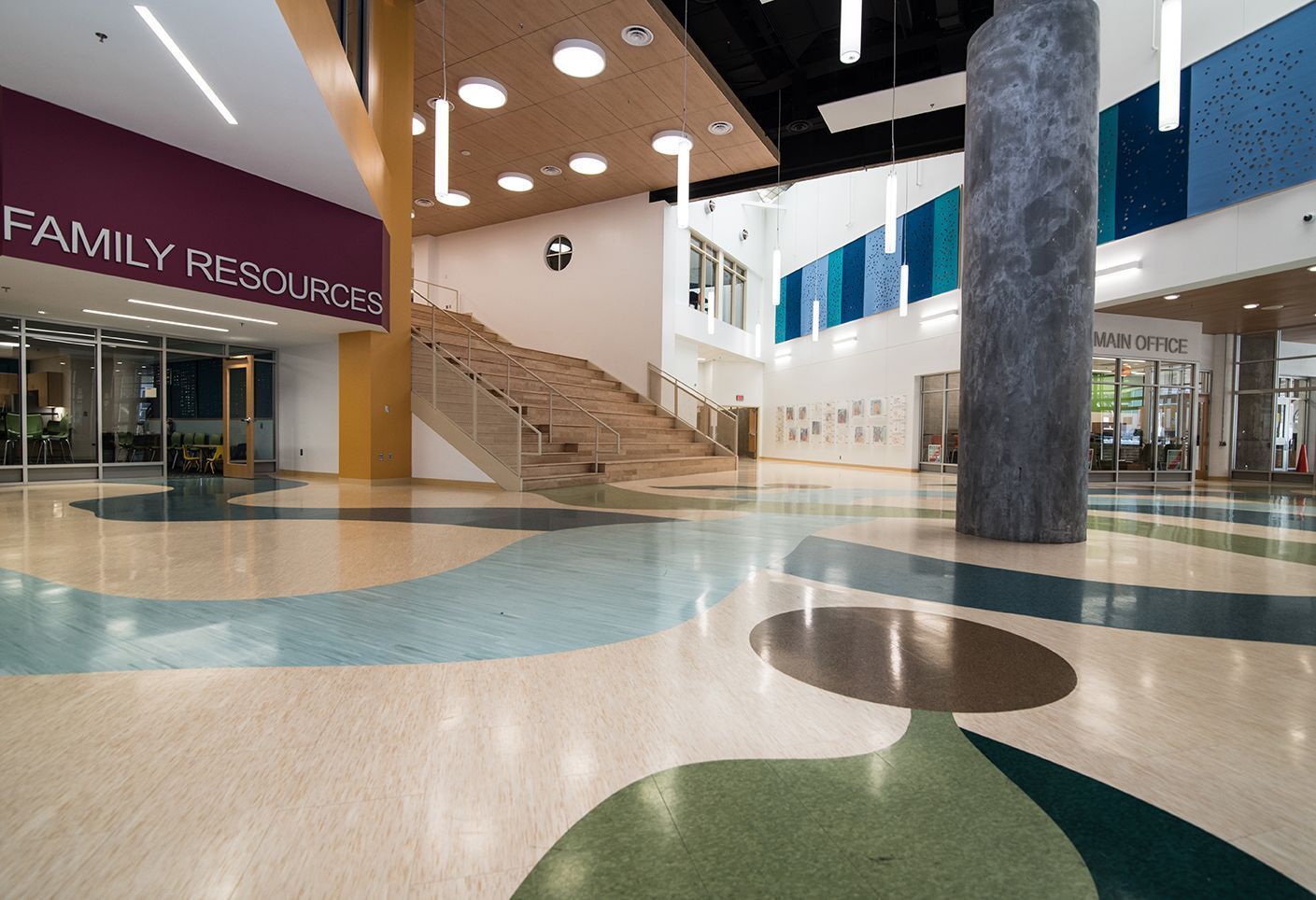 Lobby with patterned flooring, staircase, and accents of purple, gold, and teal; entrance to