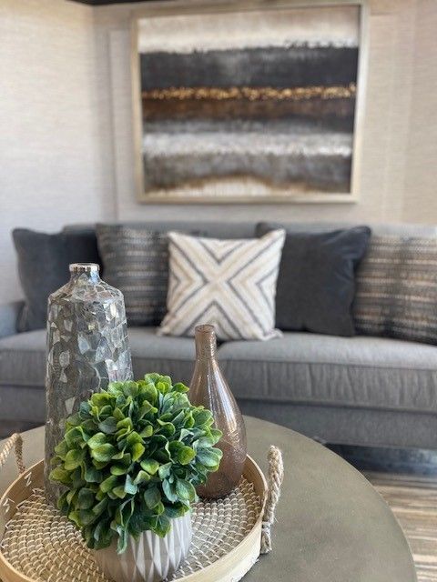 Living room with gray sofa, art, and decorative tray with greenery and vases.
