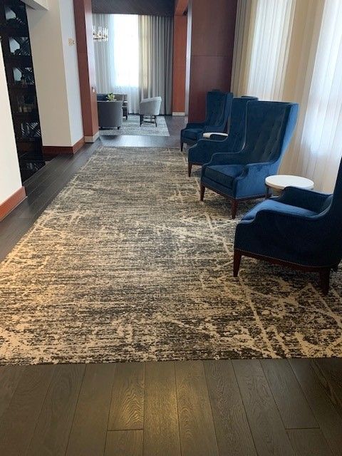 Long, abstract rug in hallway with blue armchairs and a window.