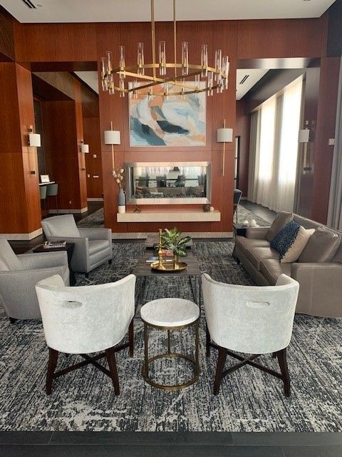 Lounge area with seating, fireplace, painting, chandelier, and a decorative rug.