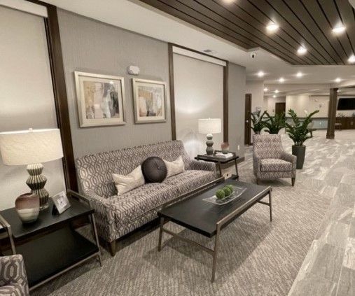 A well-lit waiting area with sofa, chair, artwork, and a coffee table.