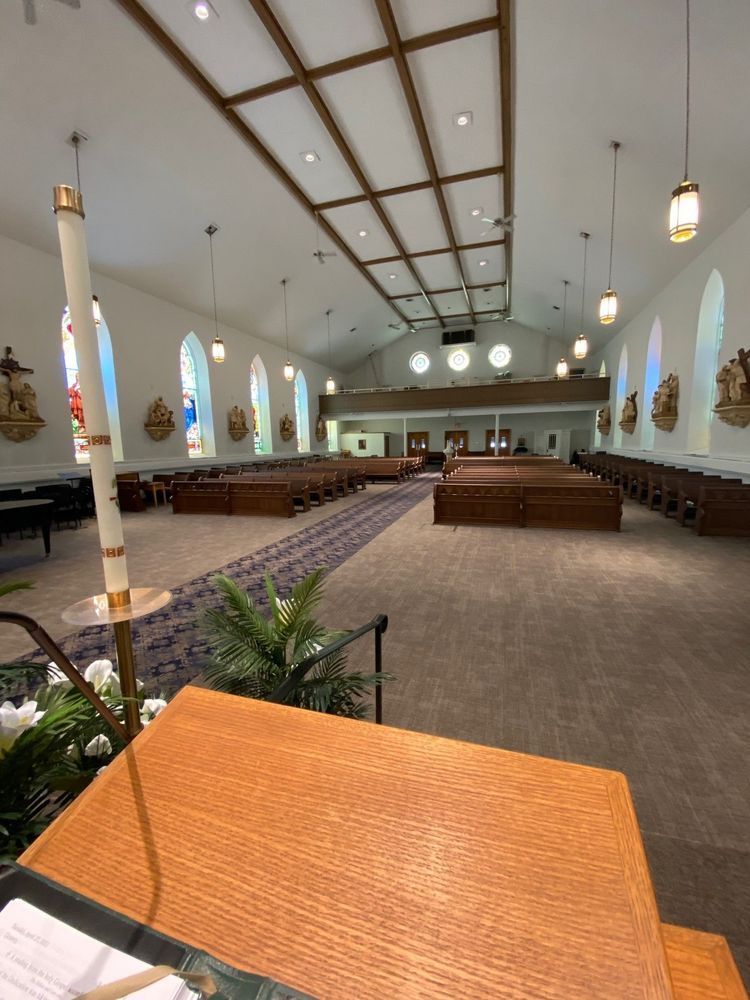 Interior of a church: rows of pews, a long aisle, stained glass windows, and a raised wooden pulpit.