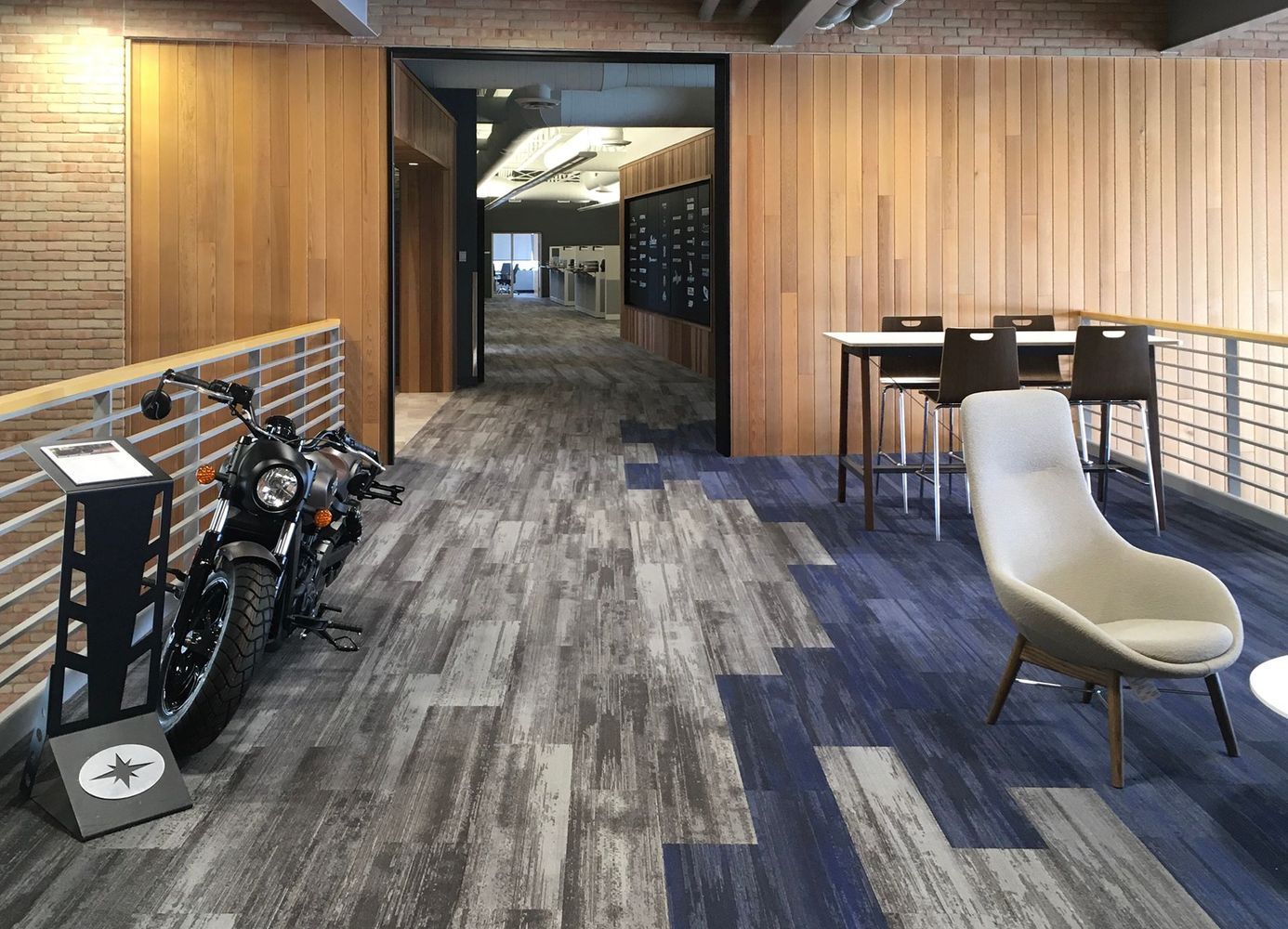 Motorcycle next to a waiting area with a modern chair, table, and wood paneling.