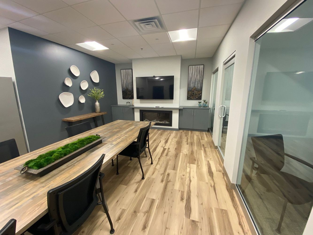 Conference room with long wooden table, blue accent wall, fireplace, and glass doors.