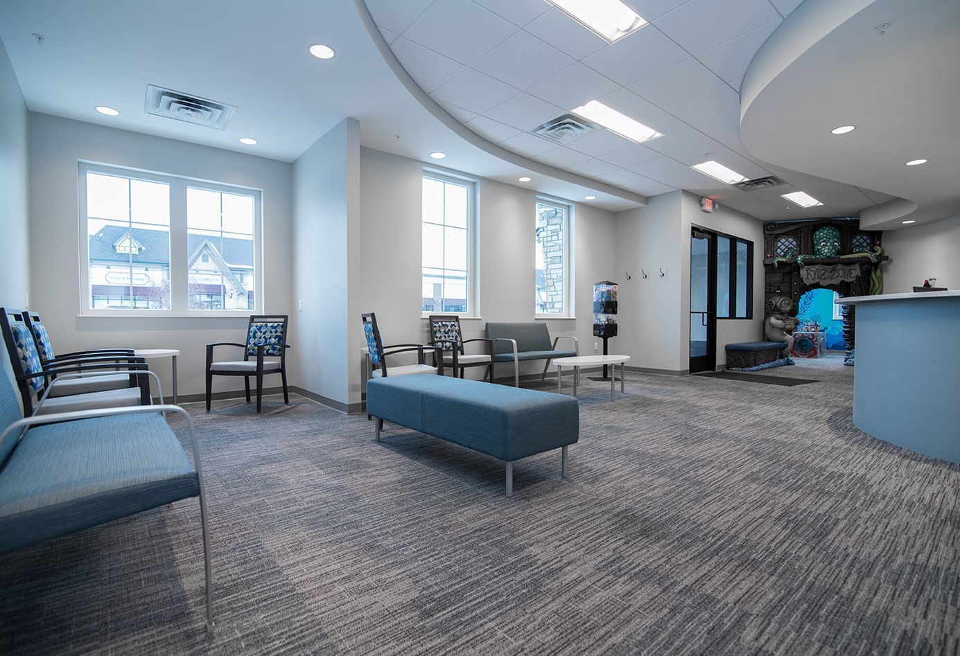 Waiting room with blue seating, windows, and a reception desk.