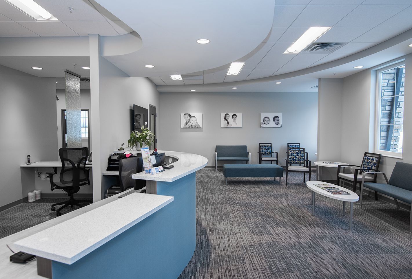 Reception area with blue and gray furniture, gray carpet, and white counter.