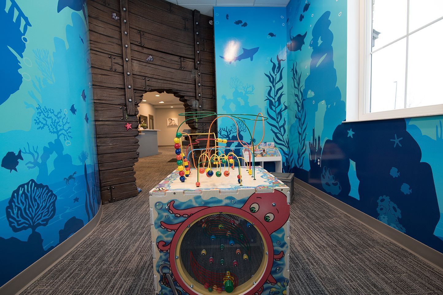 Playroom with blue ocean-themed walls, a wooden structure, and a colorful octopus-themed toy.