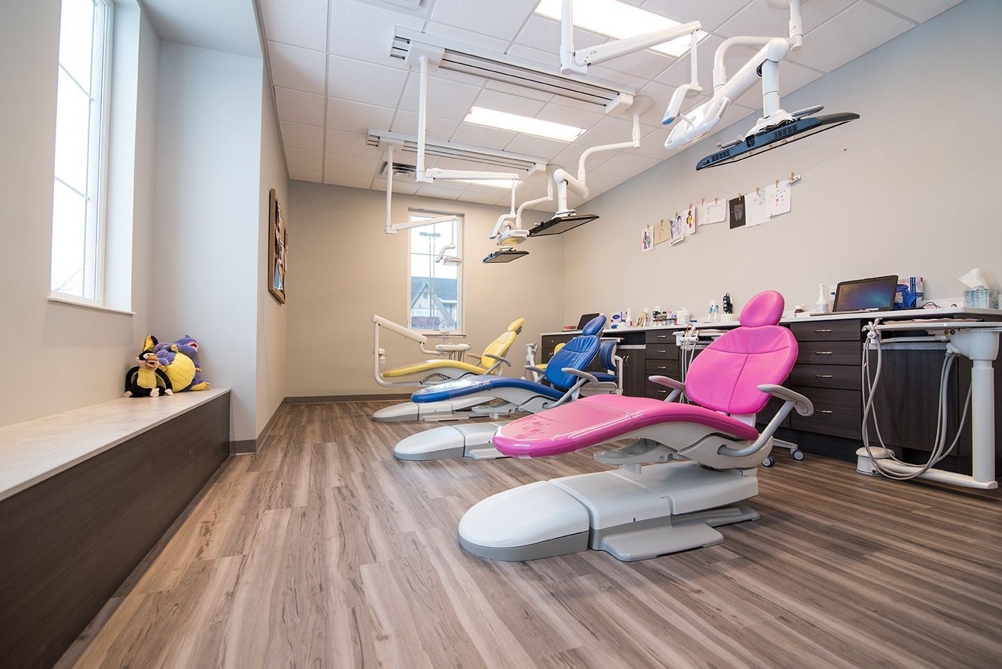 Dental office with three brightly colored chairs and overhead lights.