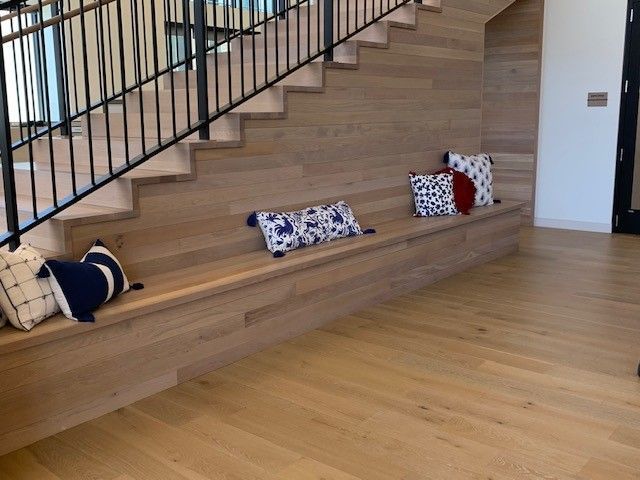 Wooden staircase with a built-in bench and pillows. Black railing.