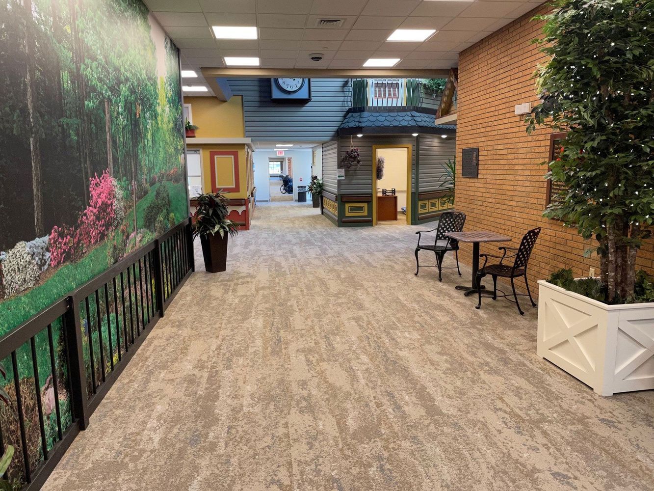 Indoor hallway with a painted forest scene, a brick wall, and decorative seating.