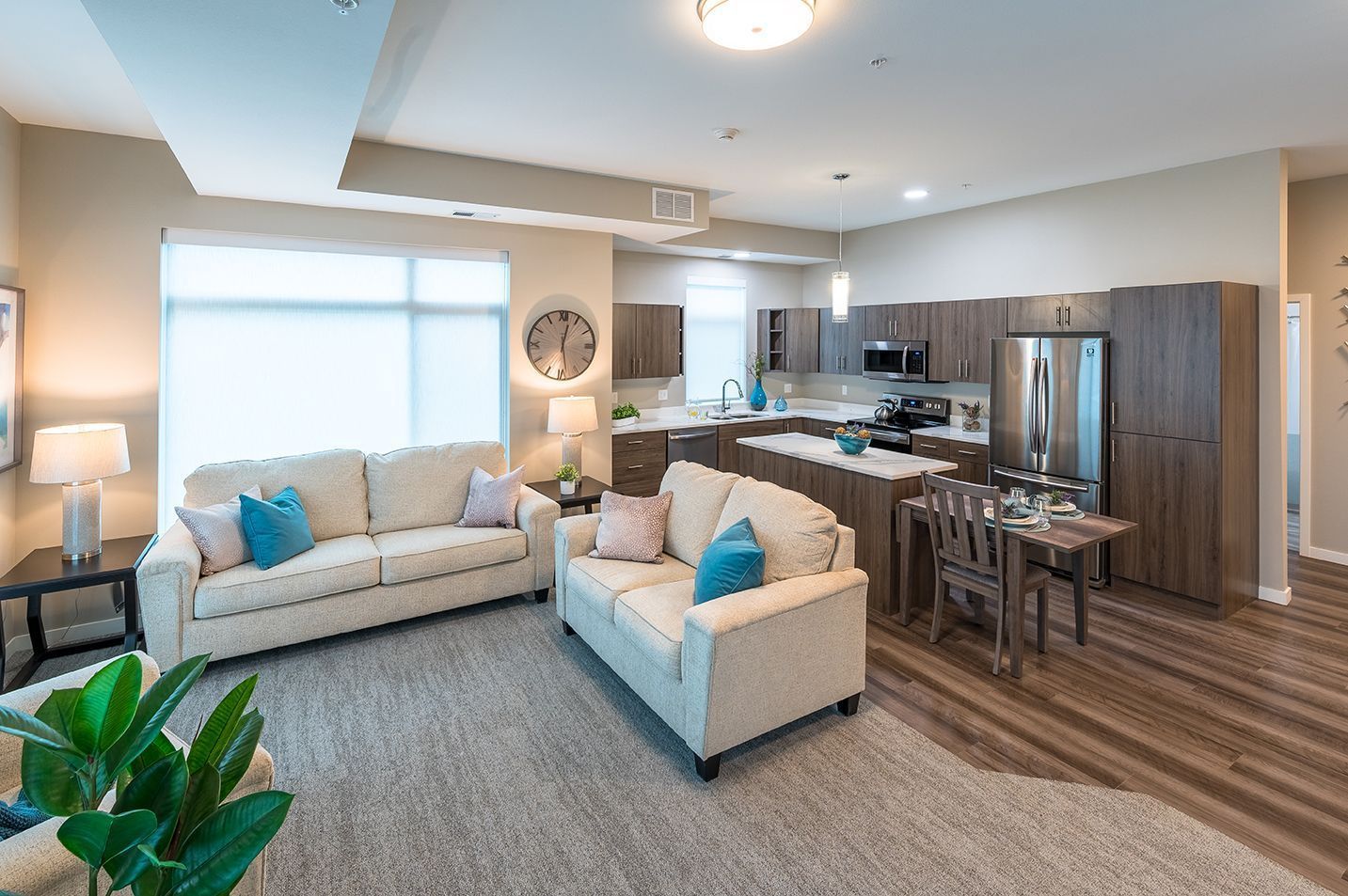 Spacious living area with kitchen, two couches, dining table, and large window.