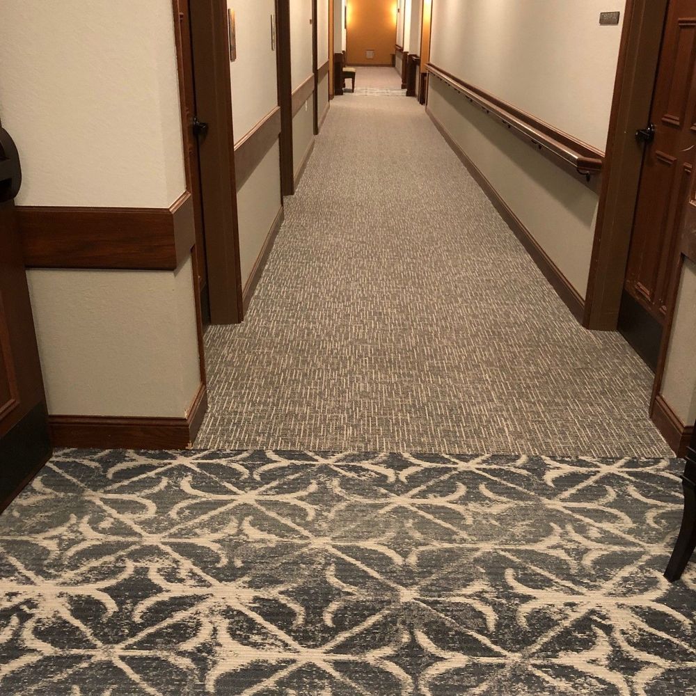Hallway with patterned carpet, doors, and a handrail.