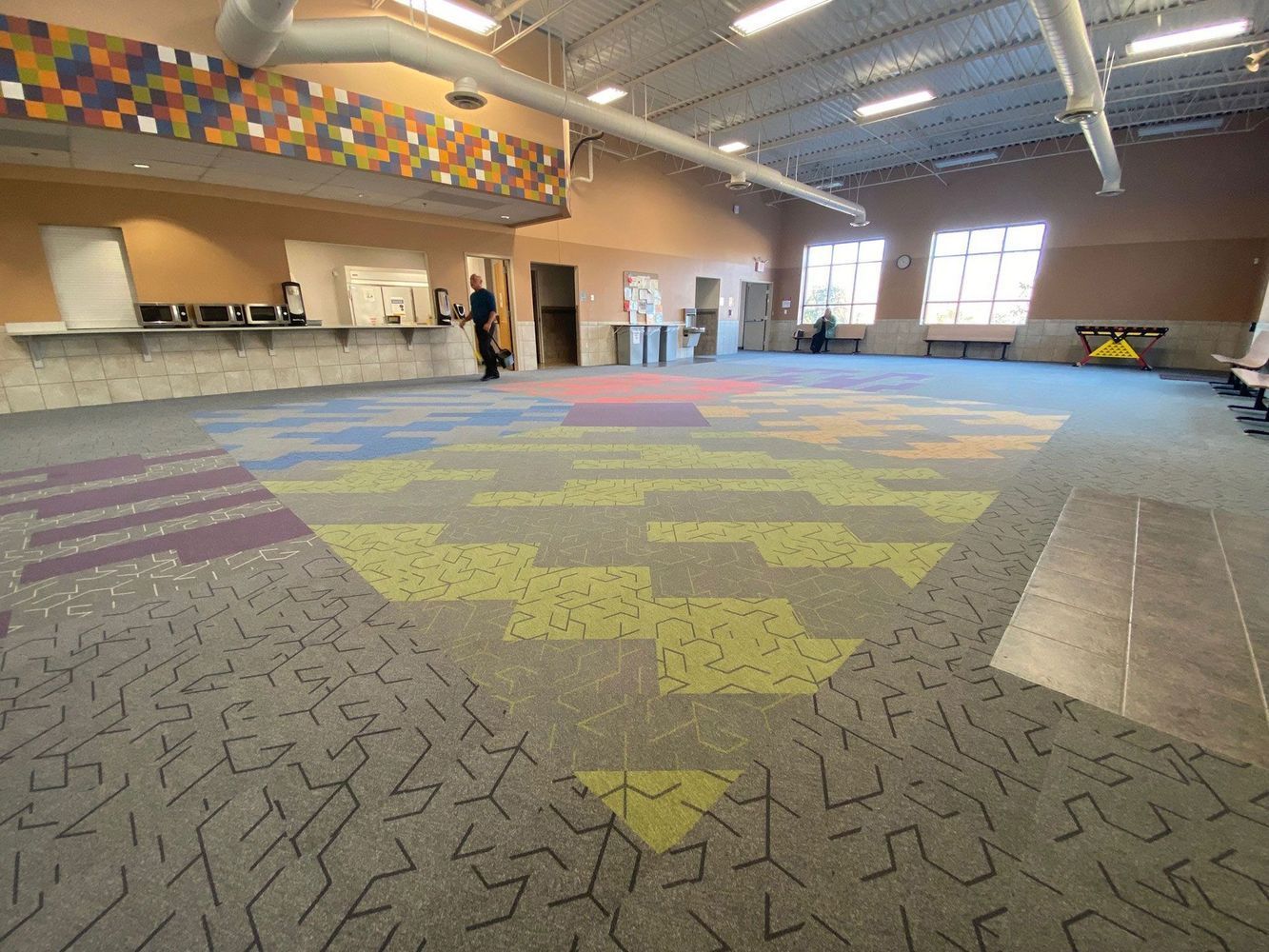 Large open room with colorful patterned carpet, counter on left, windows on right.