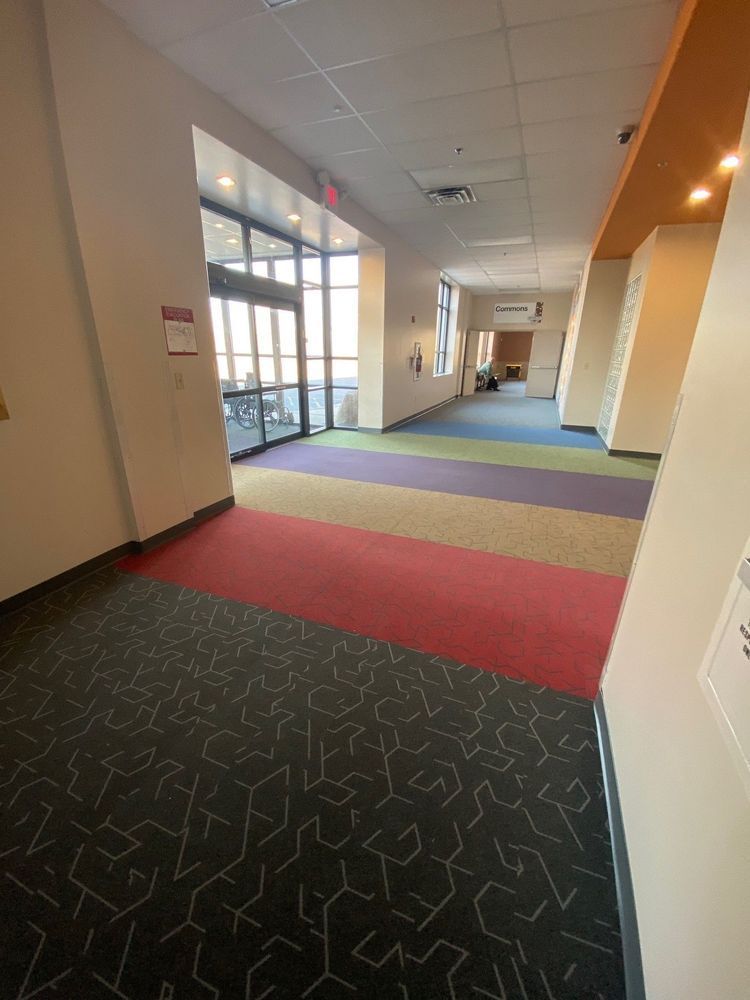 Hallway with multi-colored carpet, glass doors, and cream-colored walls.