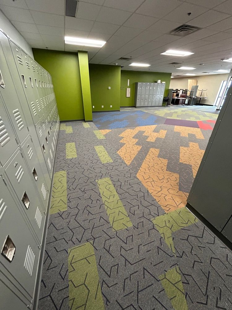 Lockers line a hallway with colorful patterned carpet and green accent walls.