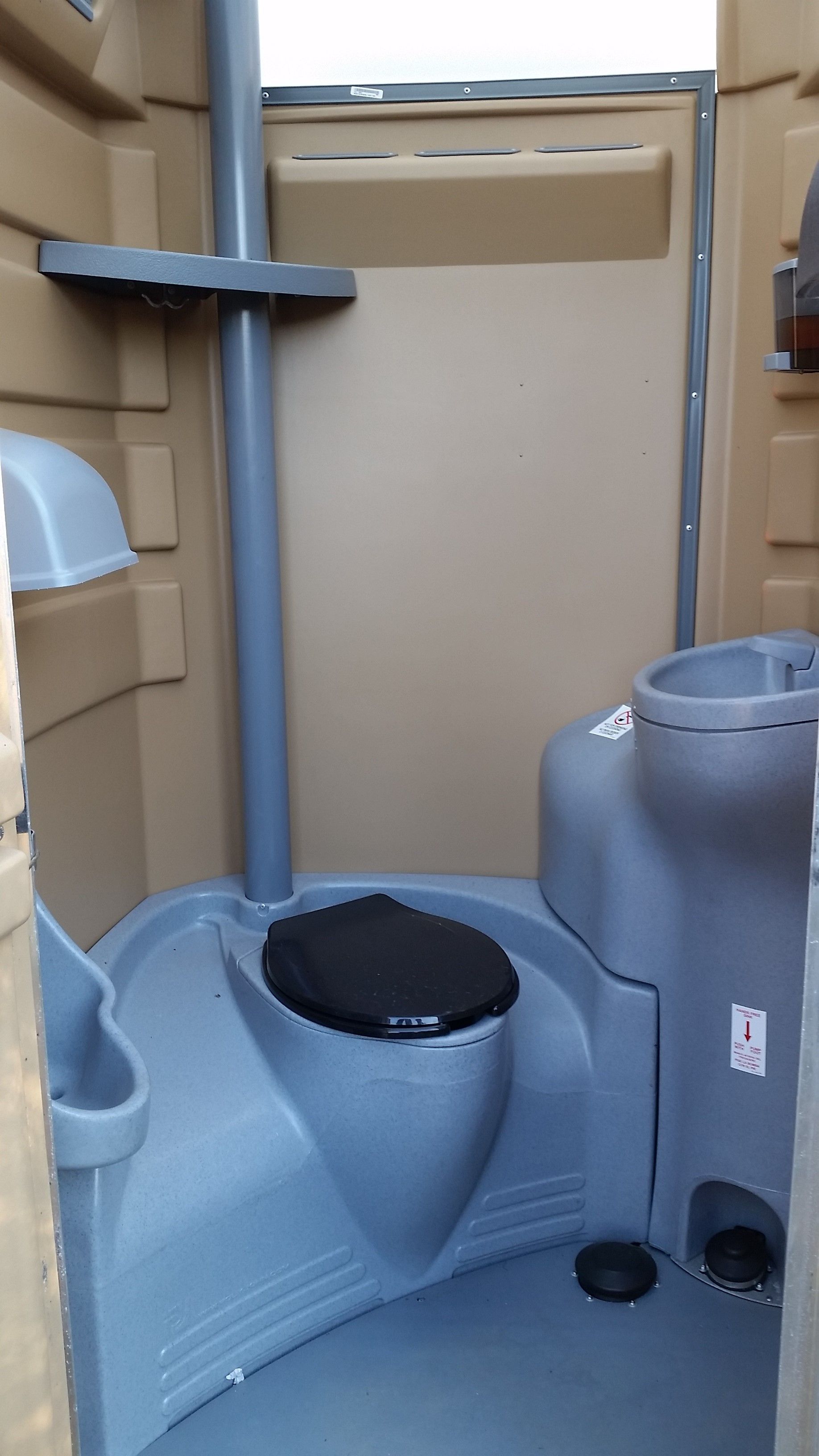 Blue portable toilet interior with toilet seat, toilet paper holder, and grab bar.