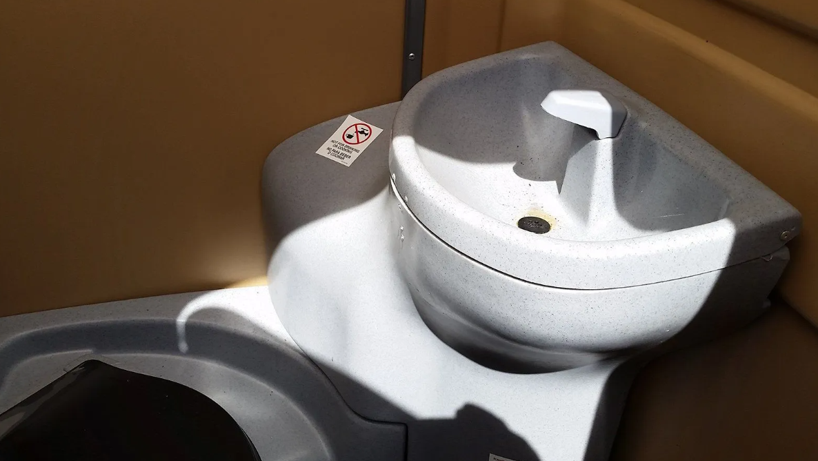 Portable toilet sink, grey plastic, in a portable toilet.