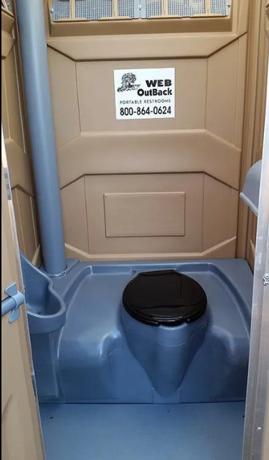 Interior of a portable toilet with a dark blue base and beige walls.