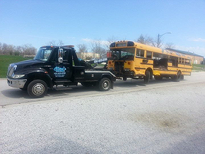 A tow truck towing a damaged school bus