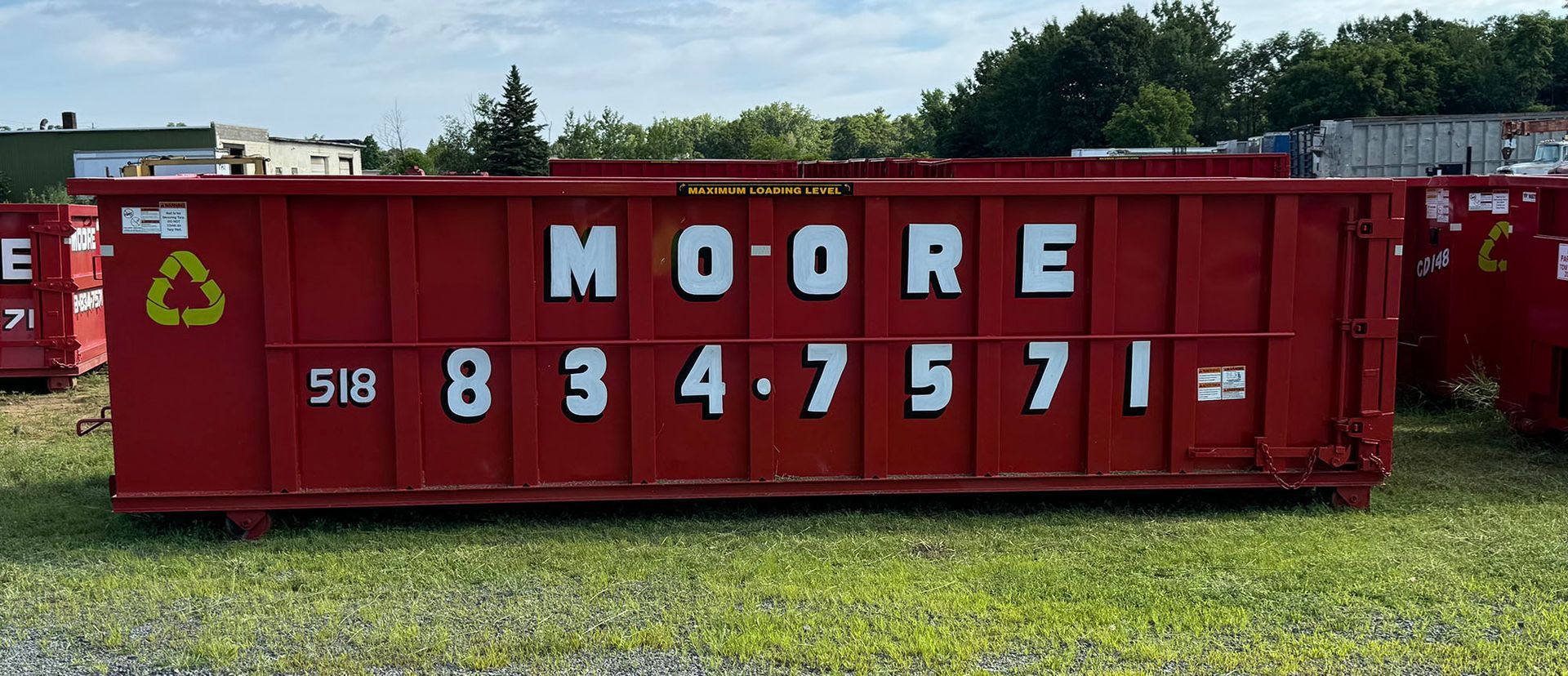 A red 30-yard dumpster is sitting in a grassy field