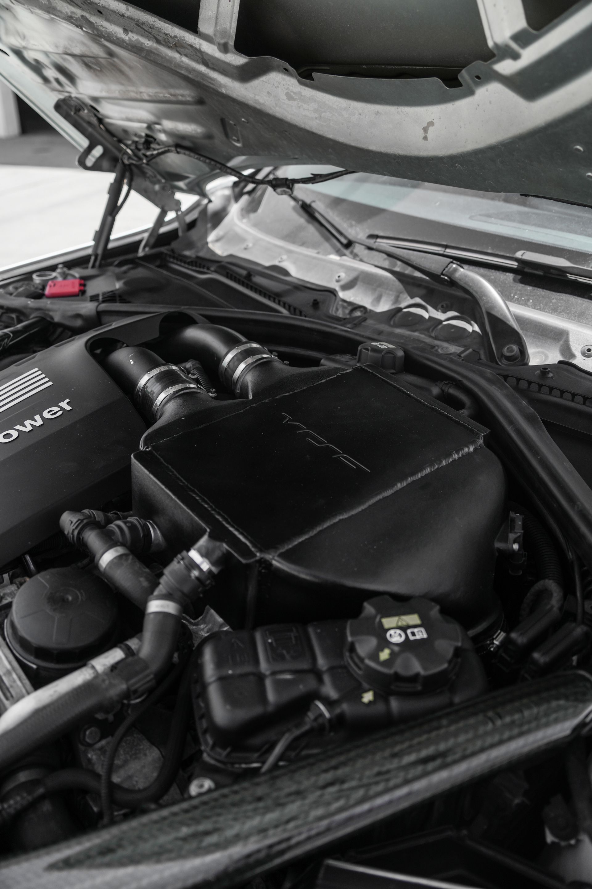 Car engine bay with black air intake components under the hood