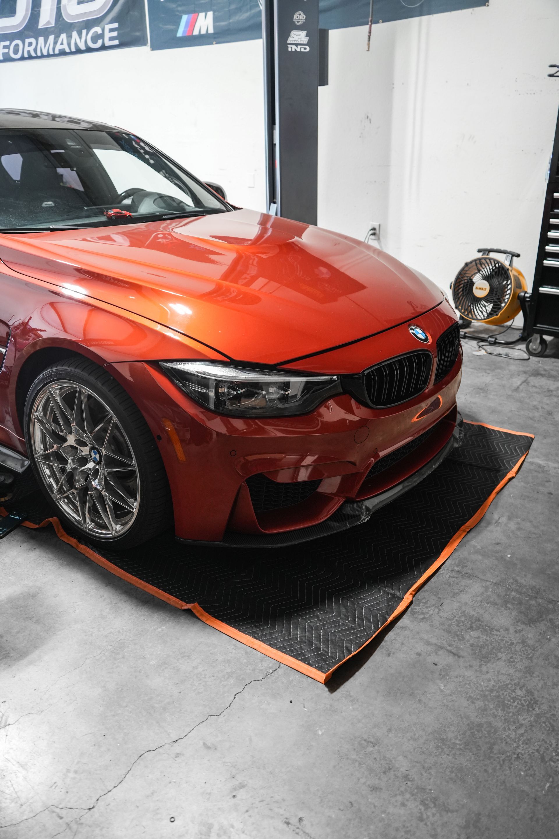 Red sports sedan on a dyno mat in an auto shop, front-left view