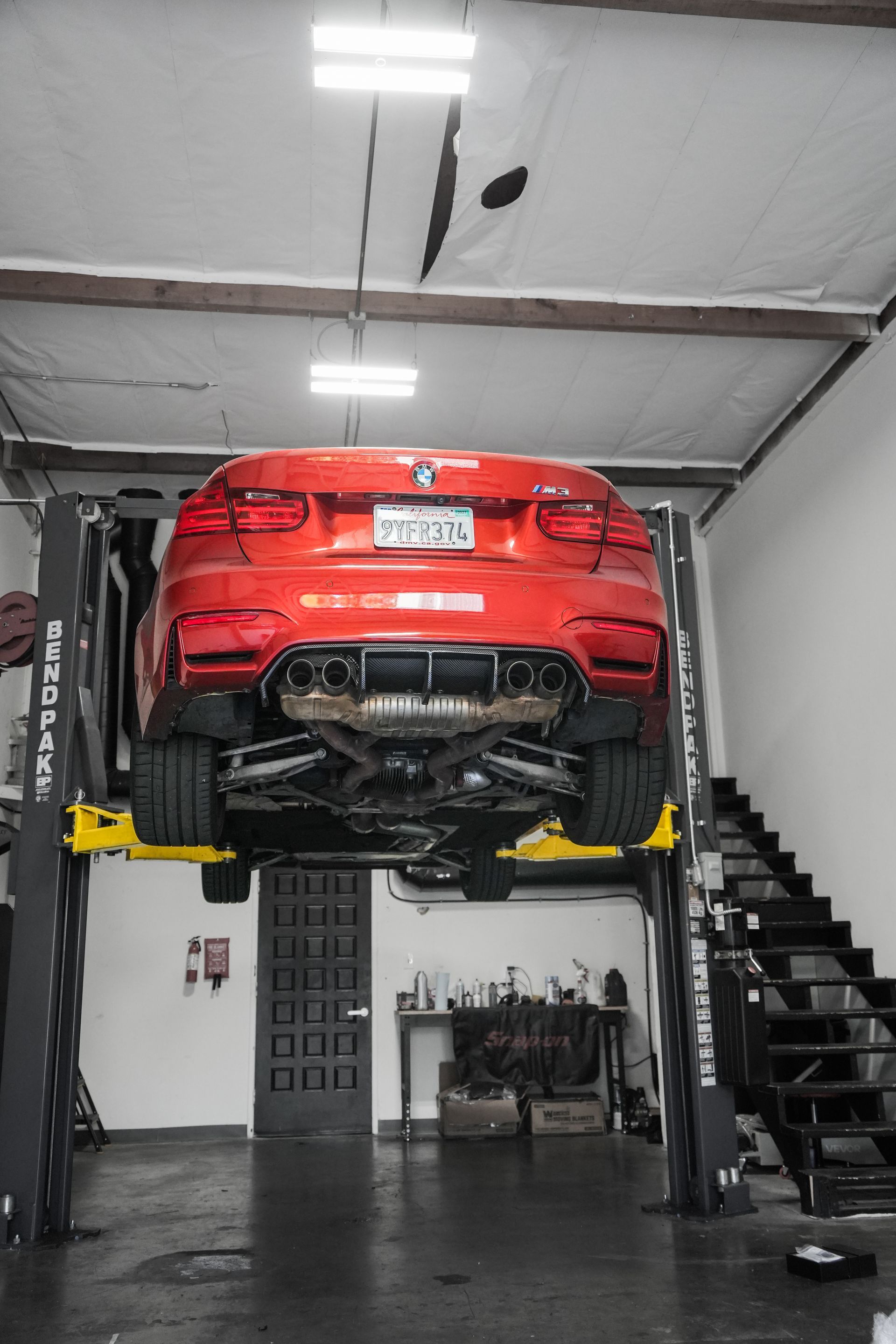 Red sports car lifted on a hoist in an auto repair garage