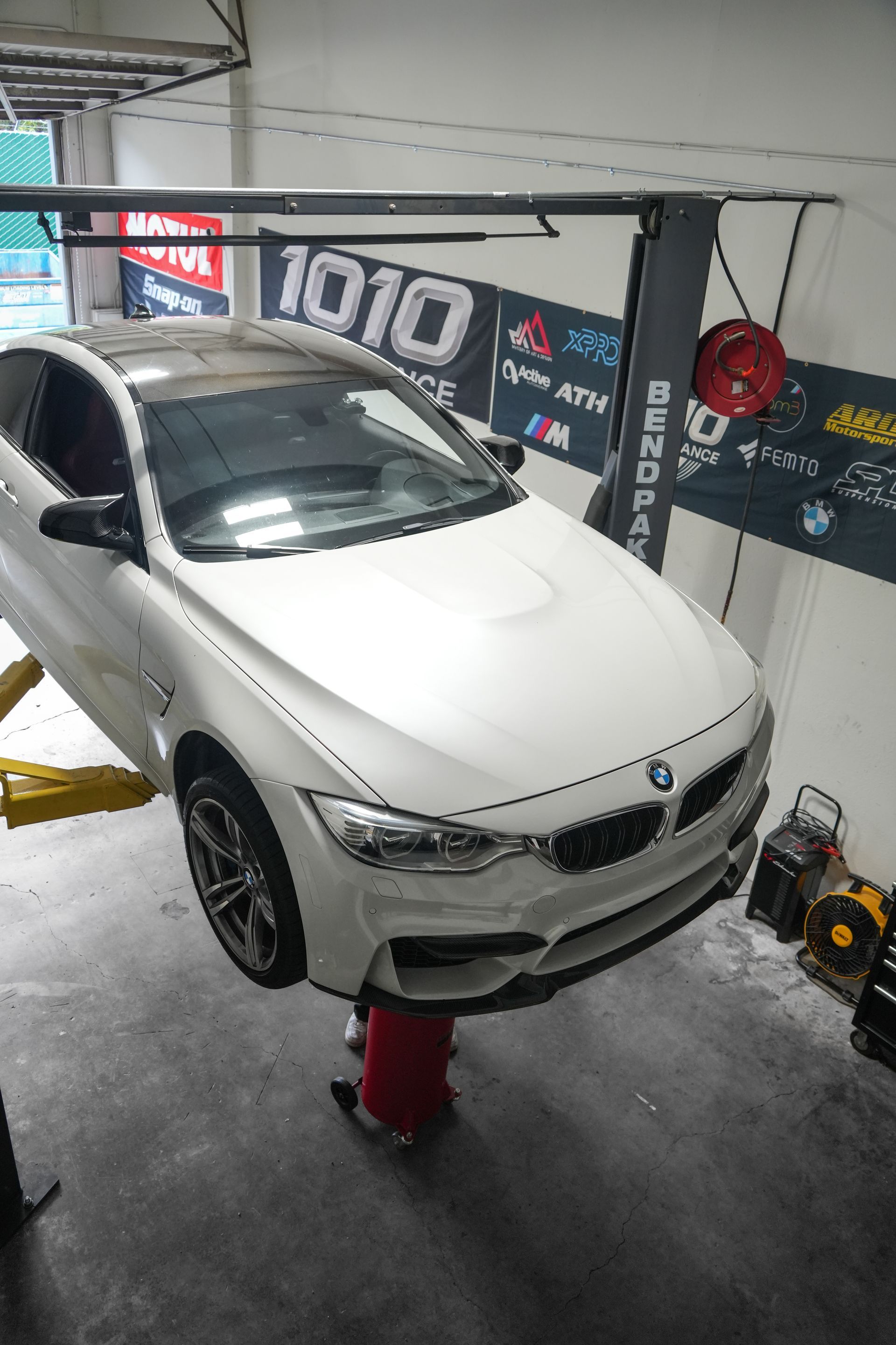 White BMW sedan on a red lift in an auto shop garage