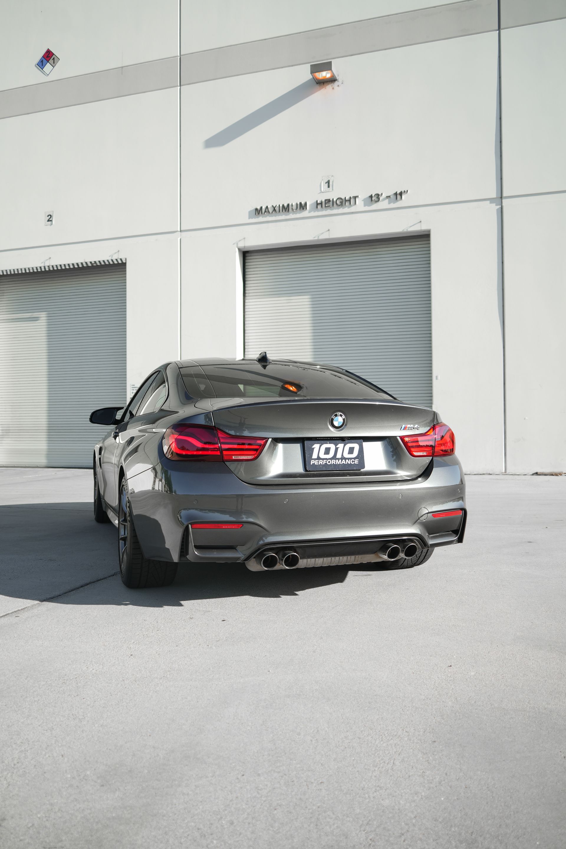 Gray BMW coupe parked outside an industrial building with closed garage doors