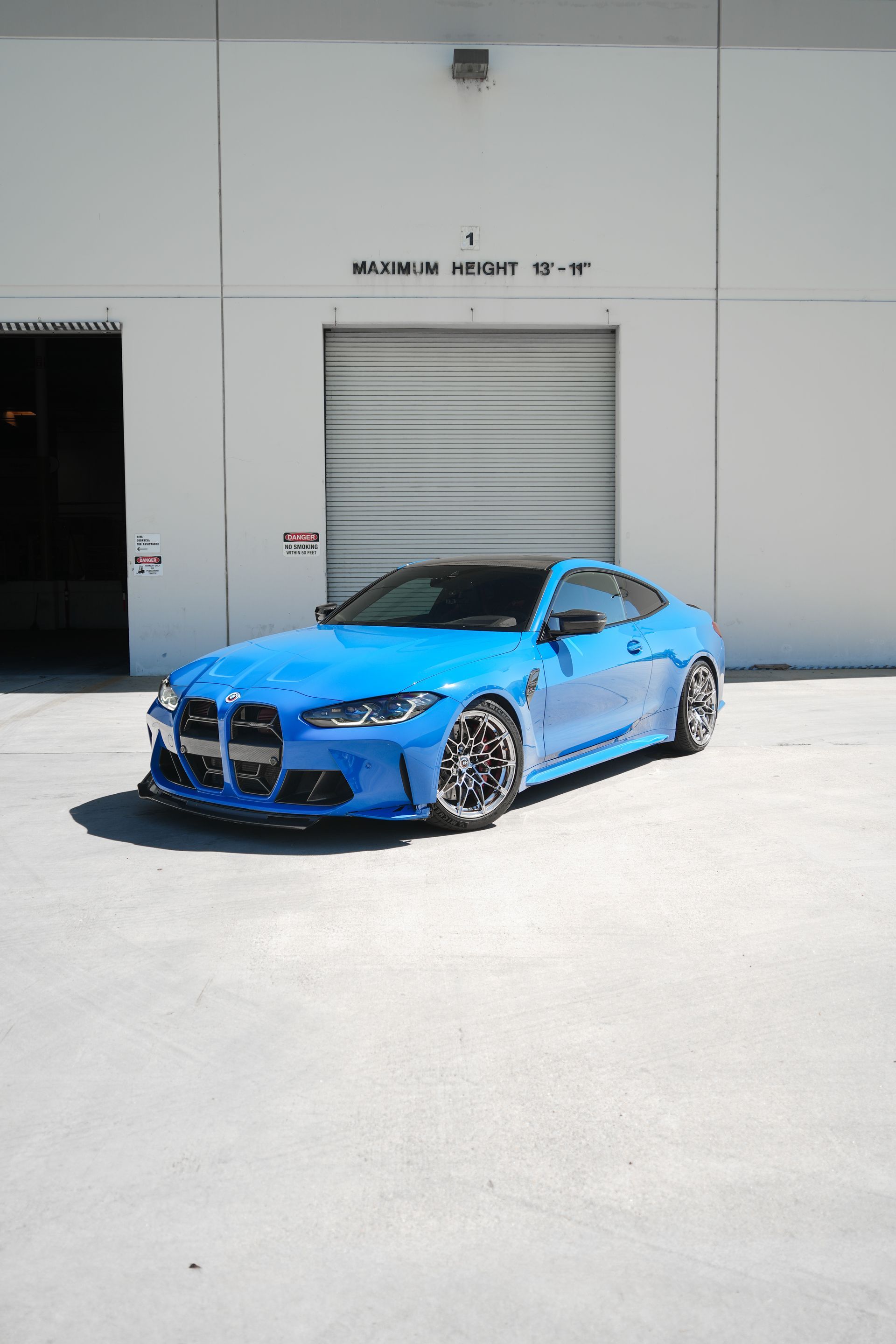 Bright blue sports coupe parked outside a warehouse in sunlight